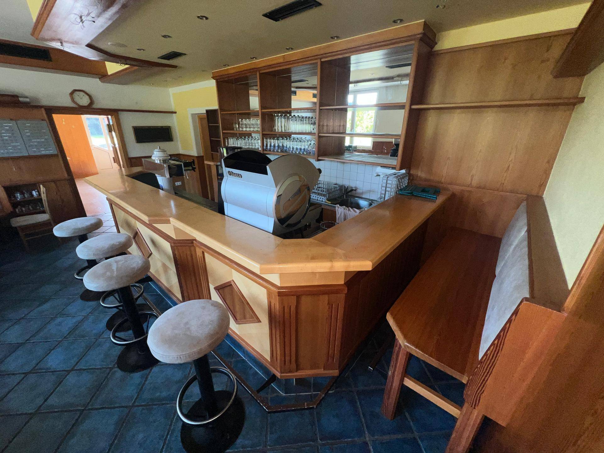 Barbereich mit Theke, Barhockern und Sitzbänken, ausgestattet für Gäste.