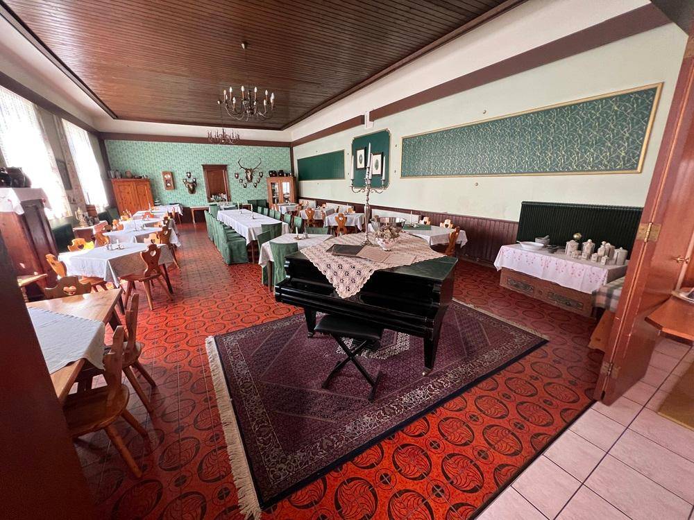 Großer Speisesaal mit Klavier, vielen Tischen und traditioneller Einrichtung, ideal für Feierlichkeiten.