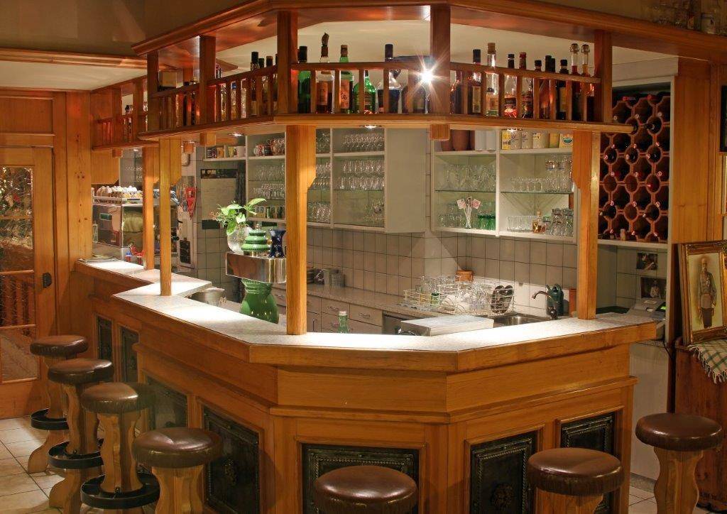 Rustikale Bar mit Holztheke, Barhockern und Flaschenregalen.
