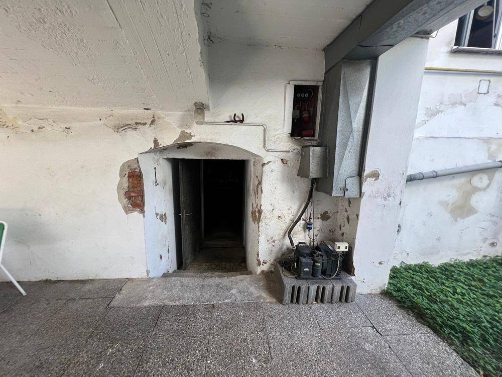 Technikbereich unter dem Carport mit alter Tür, Rohren und industrieller Ausrüstung.