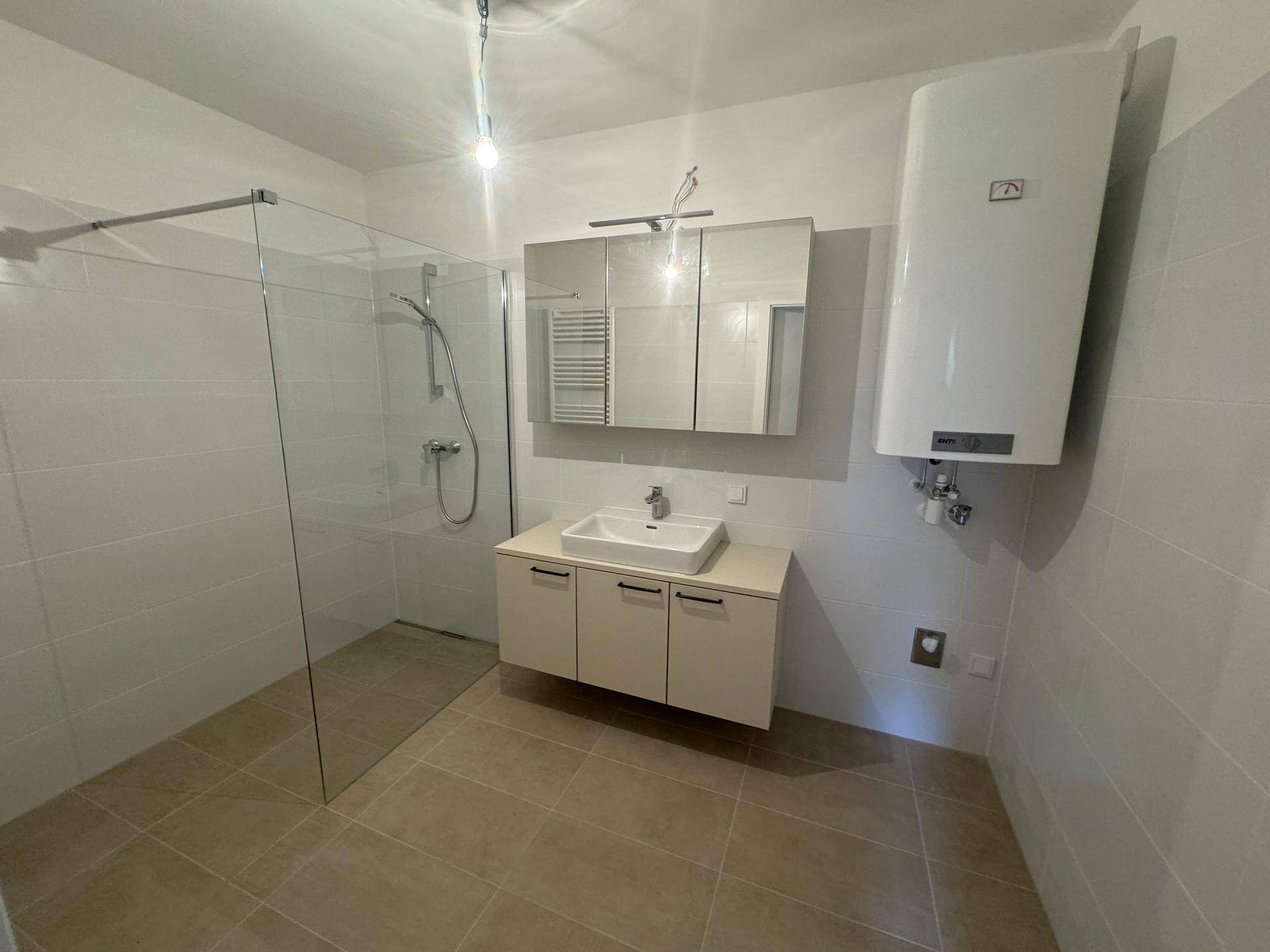 Modernes Badezimmer mit Dusche, Waschtisch und sichtbarem Warmwasserboiler.