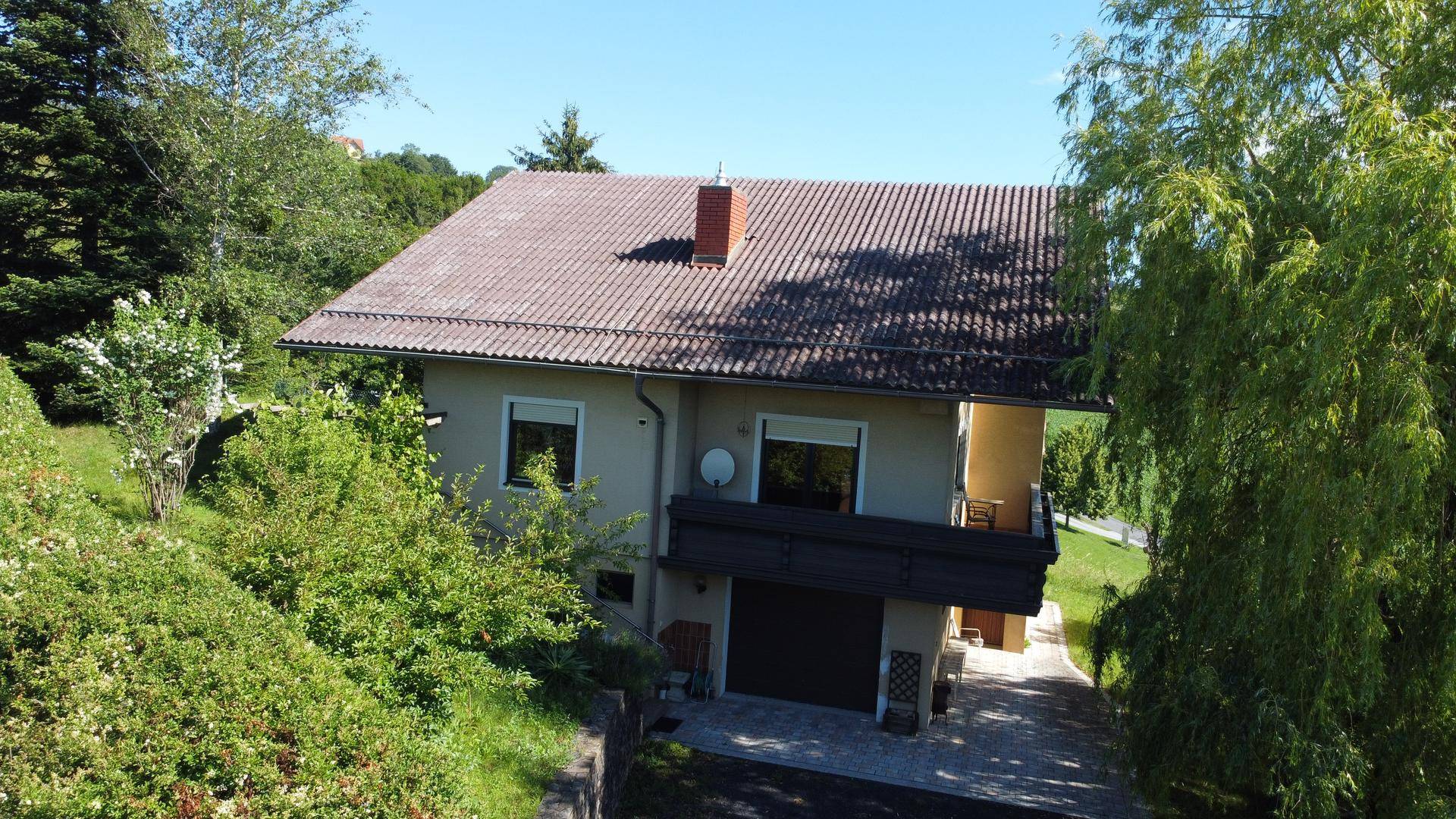 Gesamtansicht des Hauses von oben mit Dach und üppiger grüner Bepflanzung.
