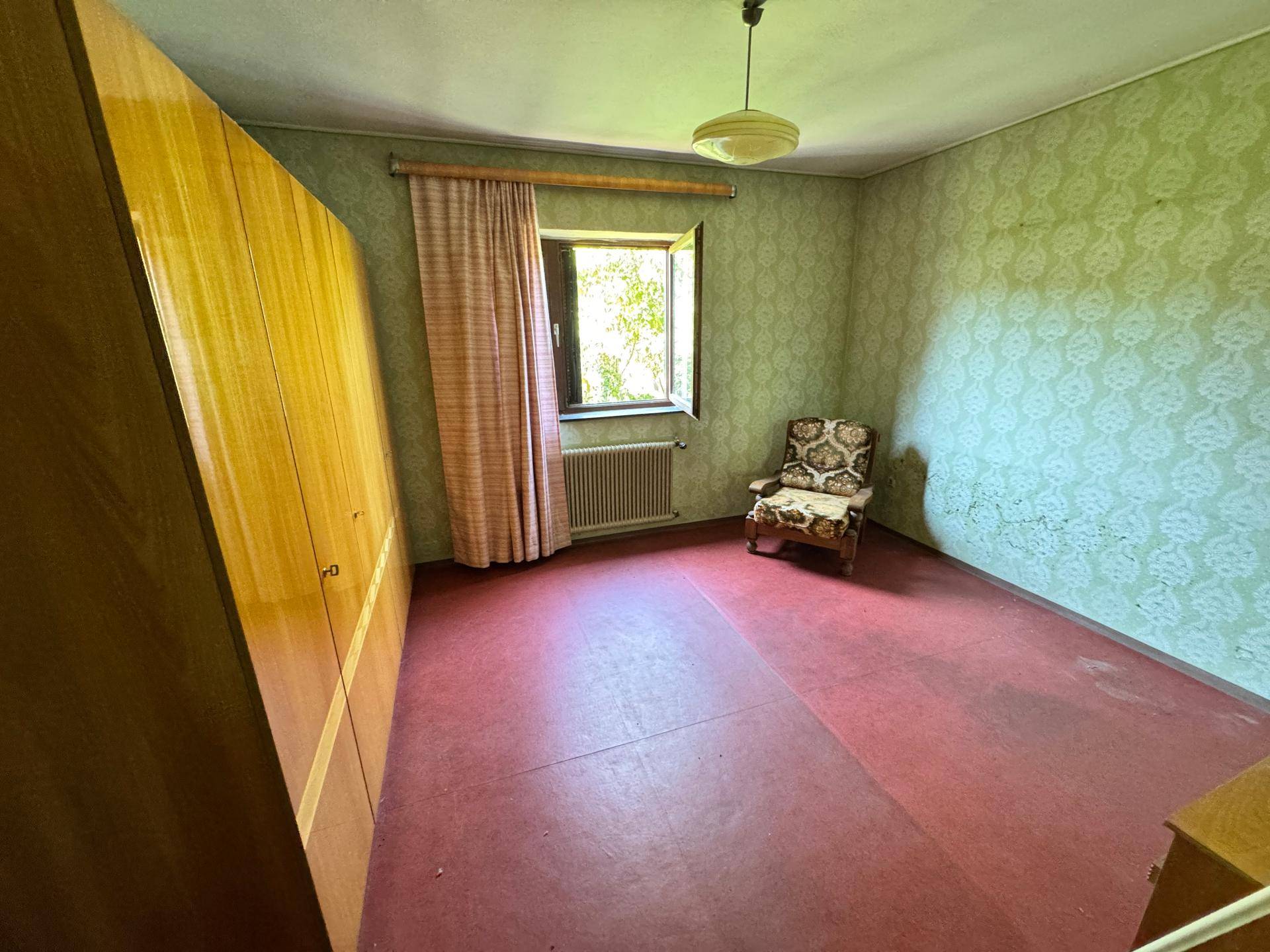Schlafzimmer mit grüner Tapete, rotem Boden und großem Kleiderschrank.
