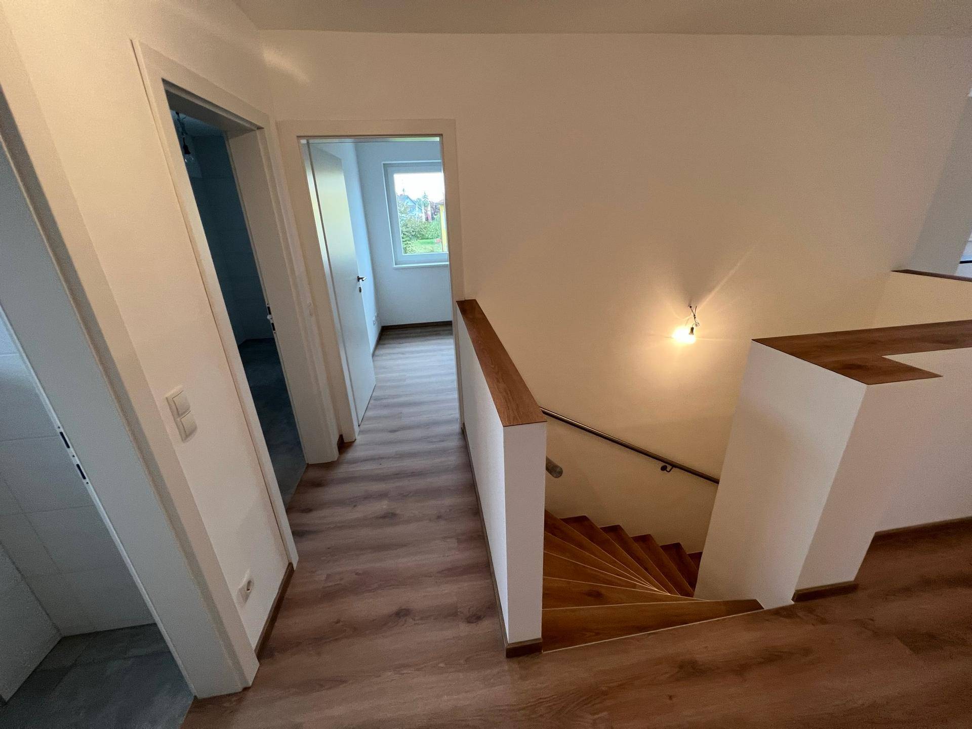 Treppenhaus mit Holzstufen und Laminatboden, das die verschiedenen Ebenen des Hauses verbindet.