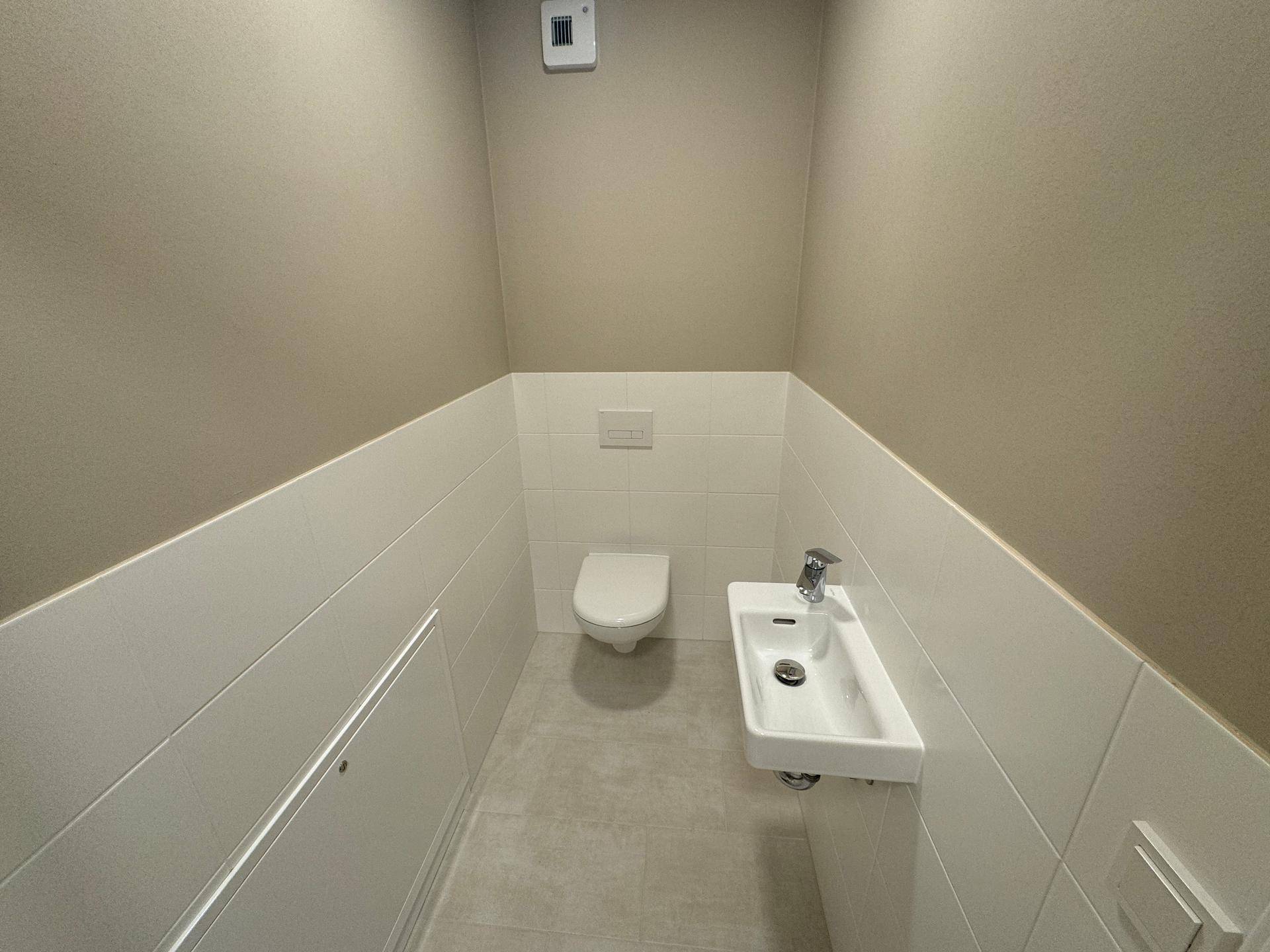 Modernes Gäste-WC mit wandhängender Toilette und kleinem Handwaschbecken.