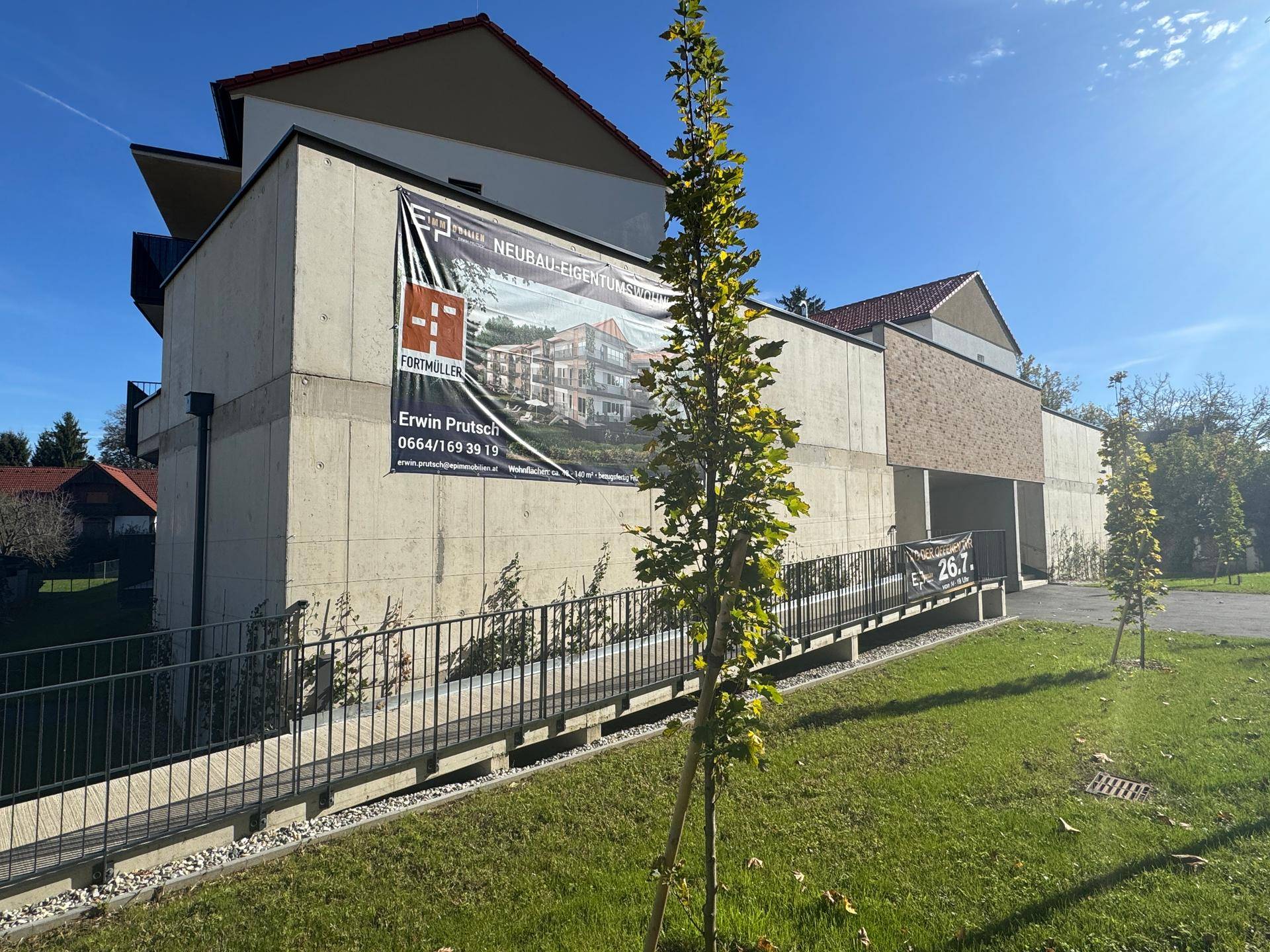 Modernes Gebäude mit Werbebanner und einer barrierefreien Rampe für Rollstuhlfahrer.