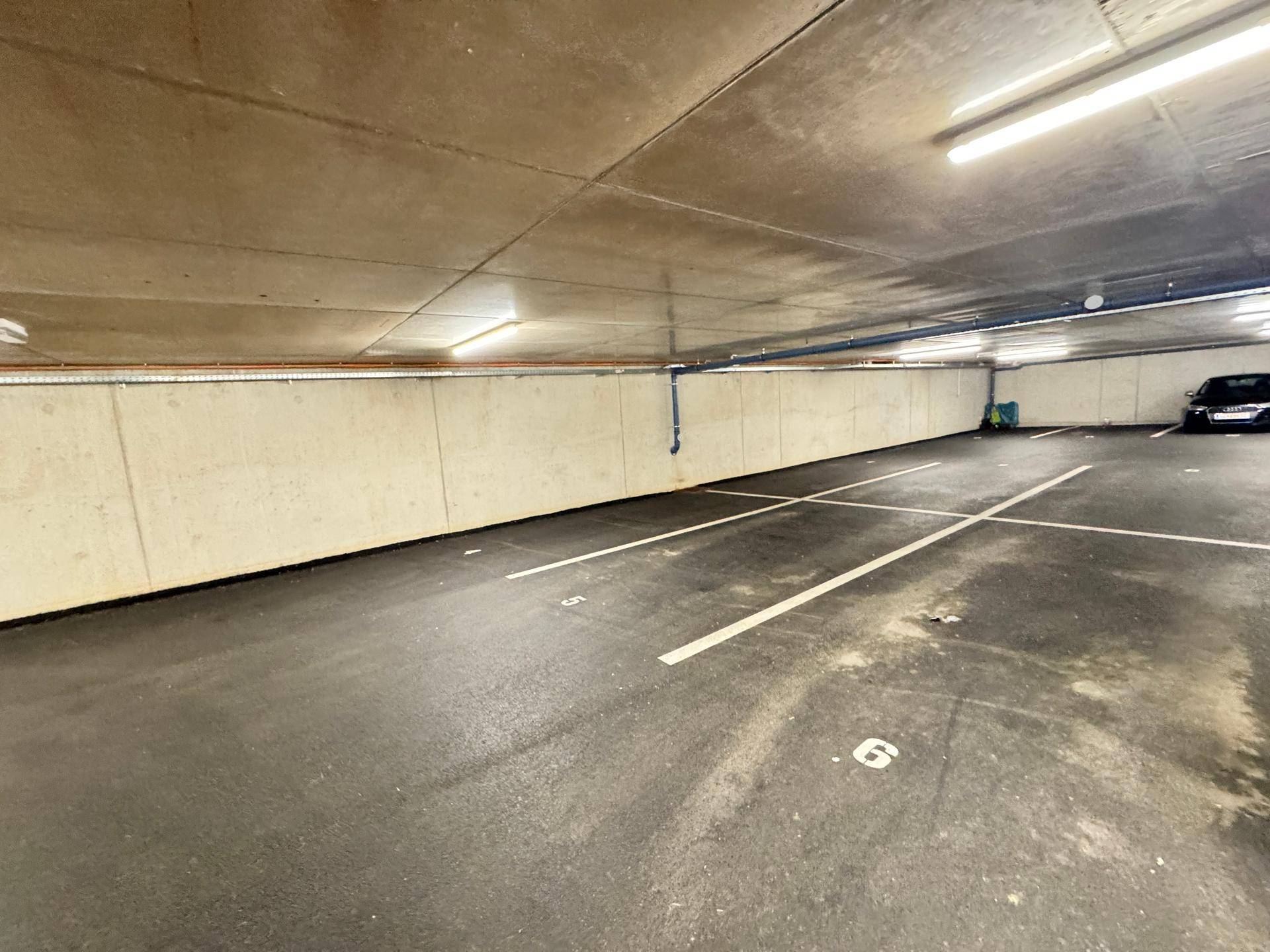 Leere Parkplätze in einer sauberen Tiefgarage mit Betonwänden.