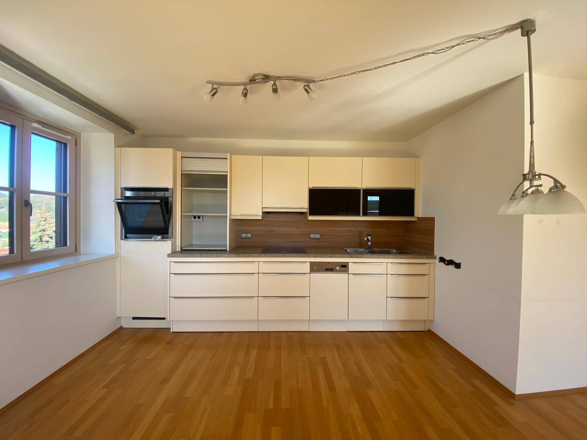 Moderne Einbauküche mit hellen Fronten, Holzdetails und integrierten Geräten.