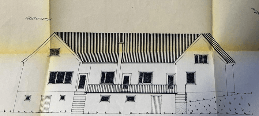 Südwestansicht des Hauses mit mehreren Fenstern und einem Balkon im Obergeschoss.
