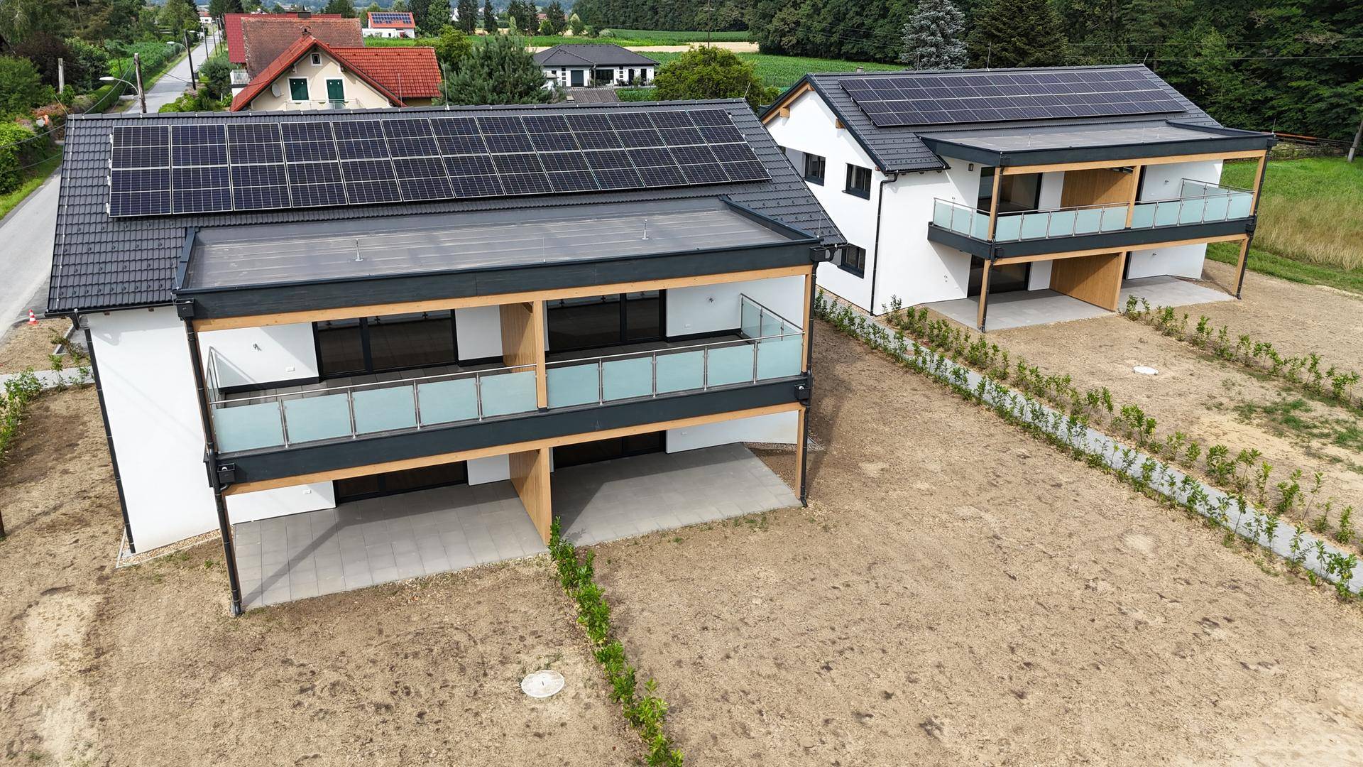 Luftaufnahme von zwei modernen Doppelhaushälften mit Solaranlagen und unbebauten Gärten.