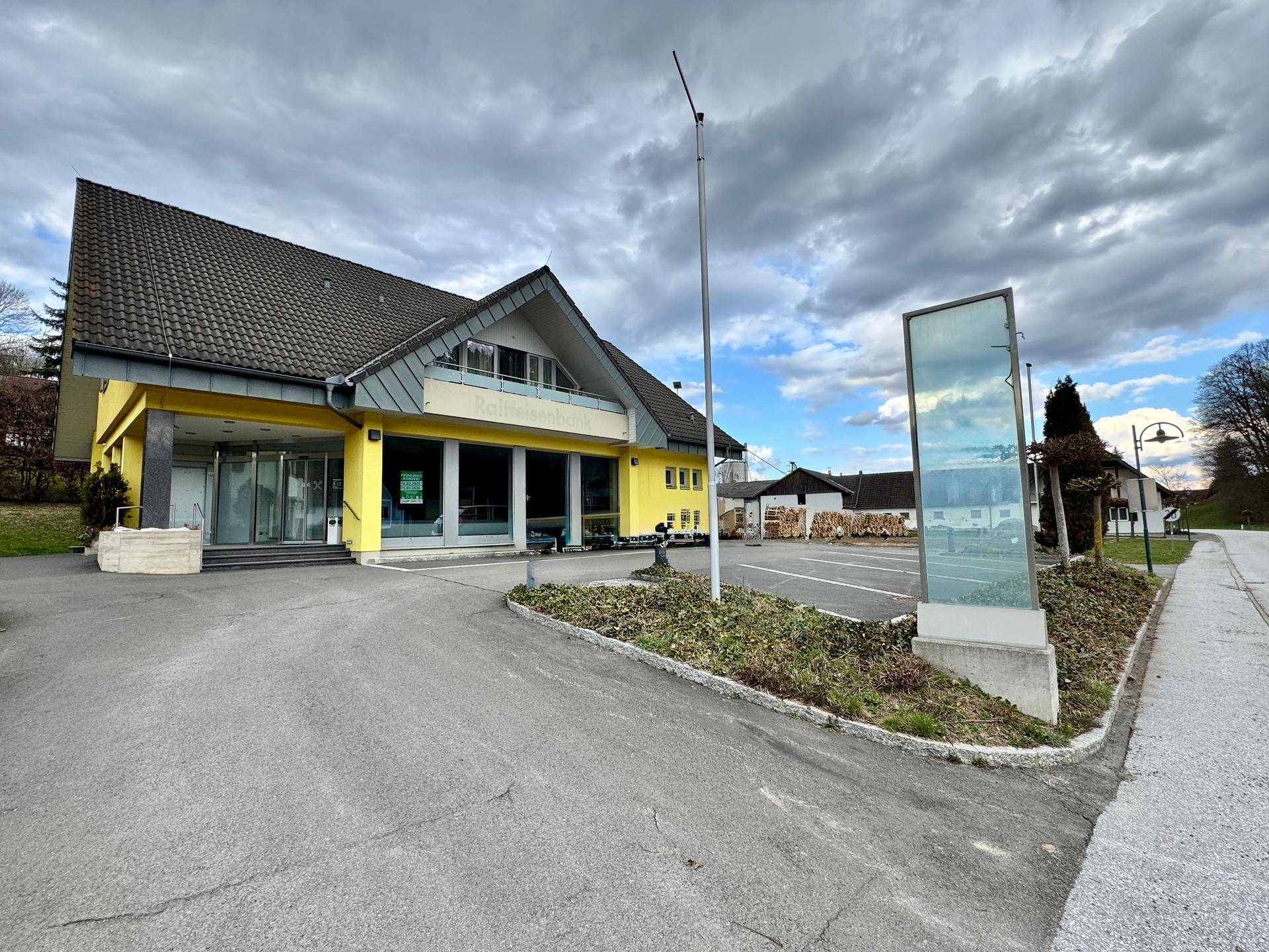 Weitwinkelansicht des gelben Gebäudes mit Parkplatz und umliegender ländlicher Landschaft.