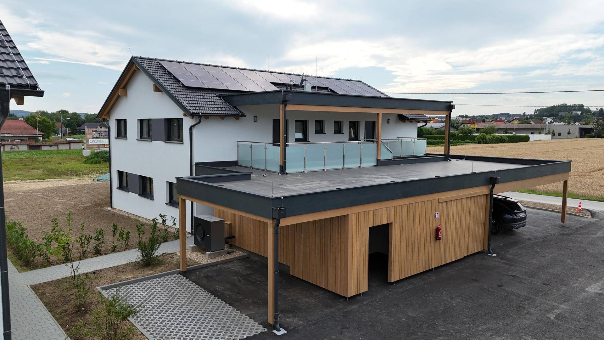 Luftaufnahme einer modernen Doppelhaushälfte mit Carport, Solaranlage und Flachdach.