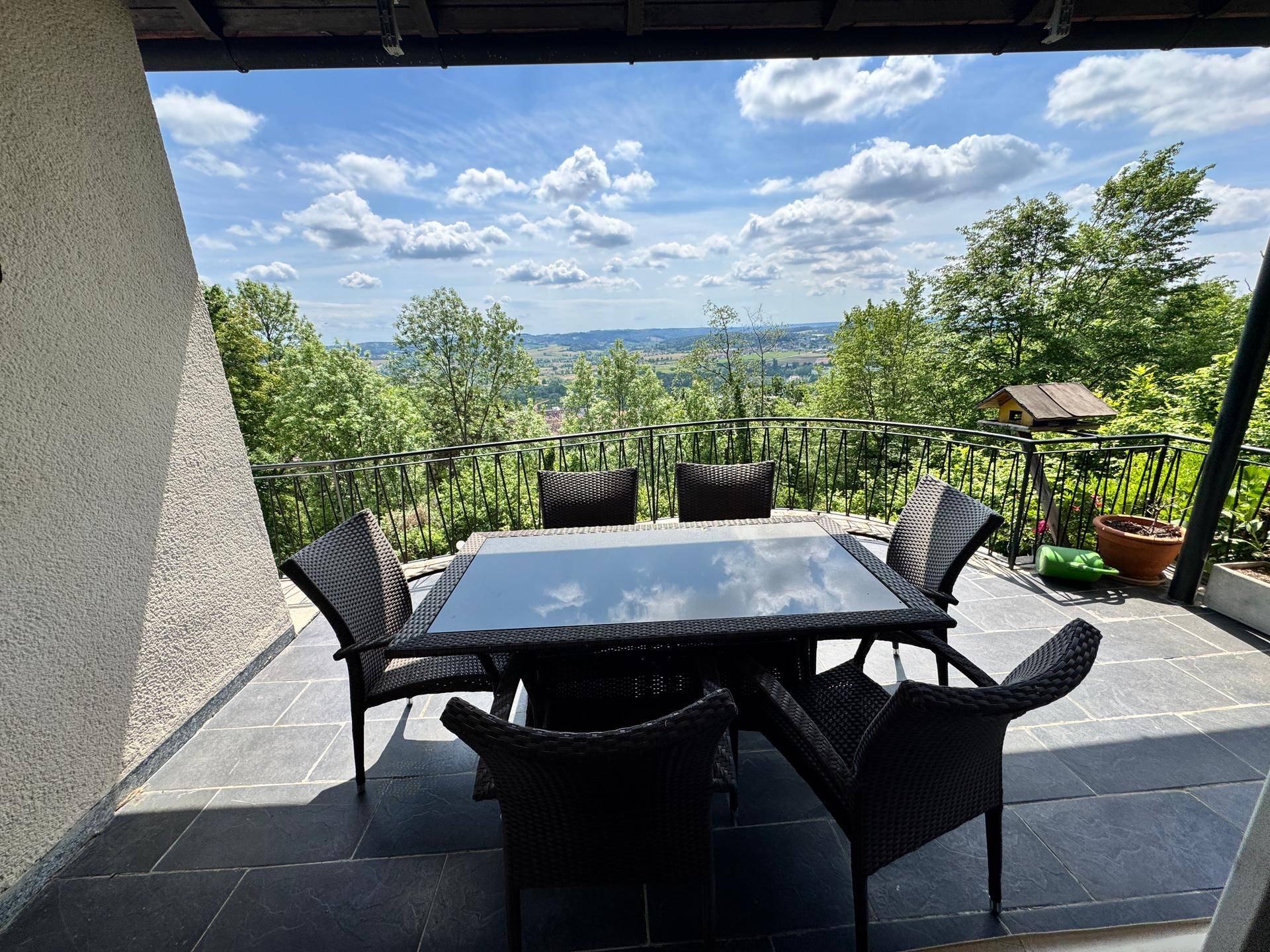Möblierter Balkon mit Esstisch und Stühlen, bietet einen weiten Blick über die Landschaft.