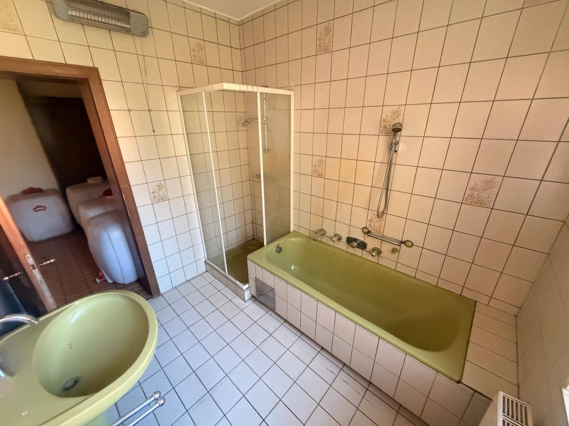 Badezimmer mit grüner Badewanne, Duschkabine und Waschbecken im Retro-Design.