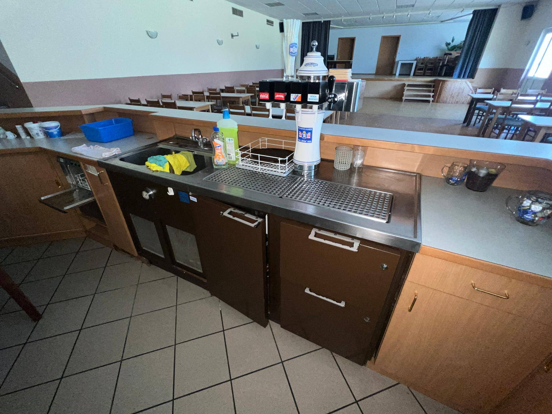 Bar-Bereich mit Spüle, Zapfanlage und Arbeitsflächen, angrenzend an einen Speisesaal.