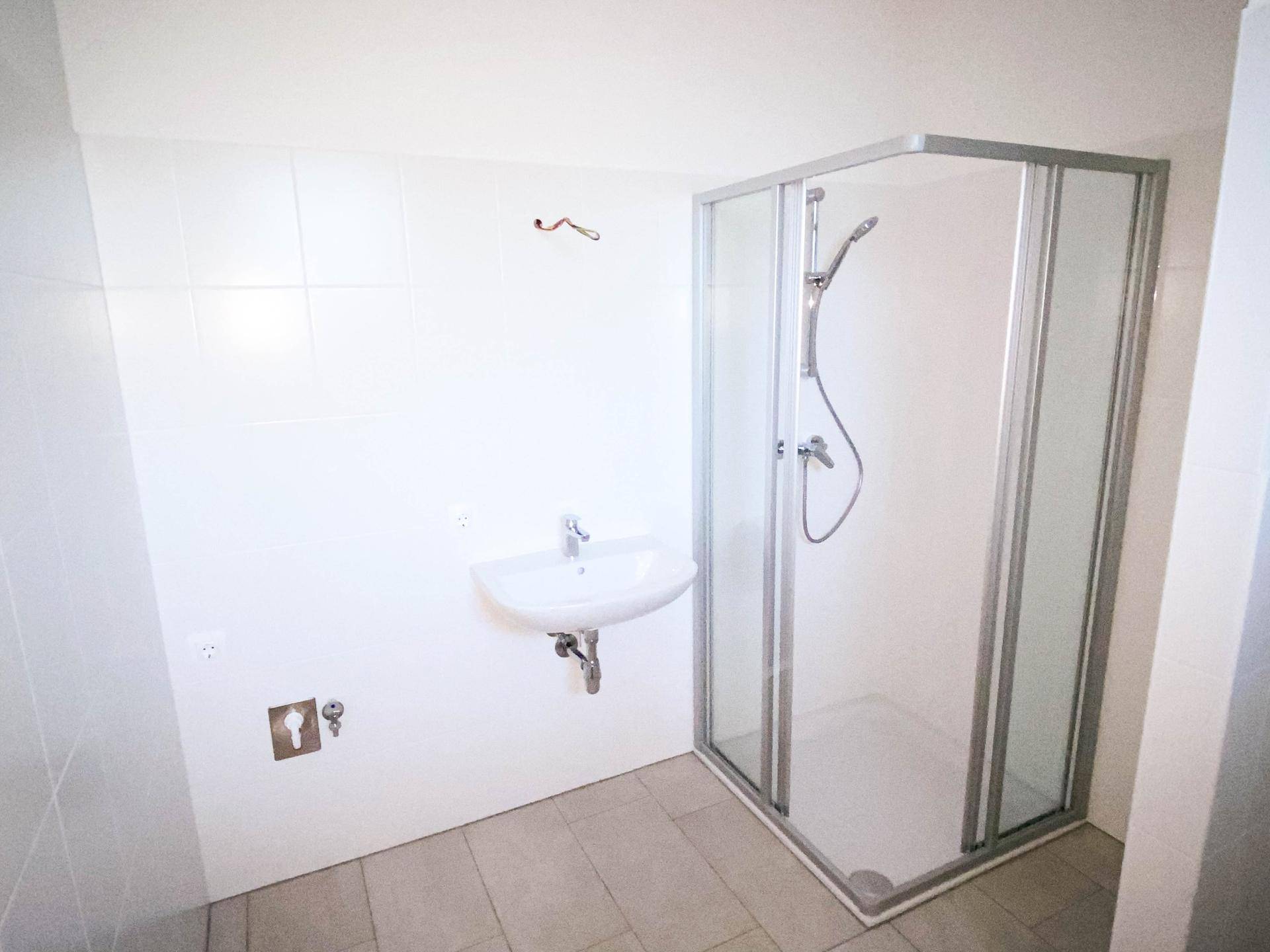Modernes Badezimmer mit weiß gefliesten Wänden, Waschbecken und einer Duschkabine.