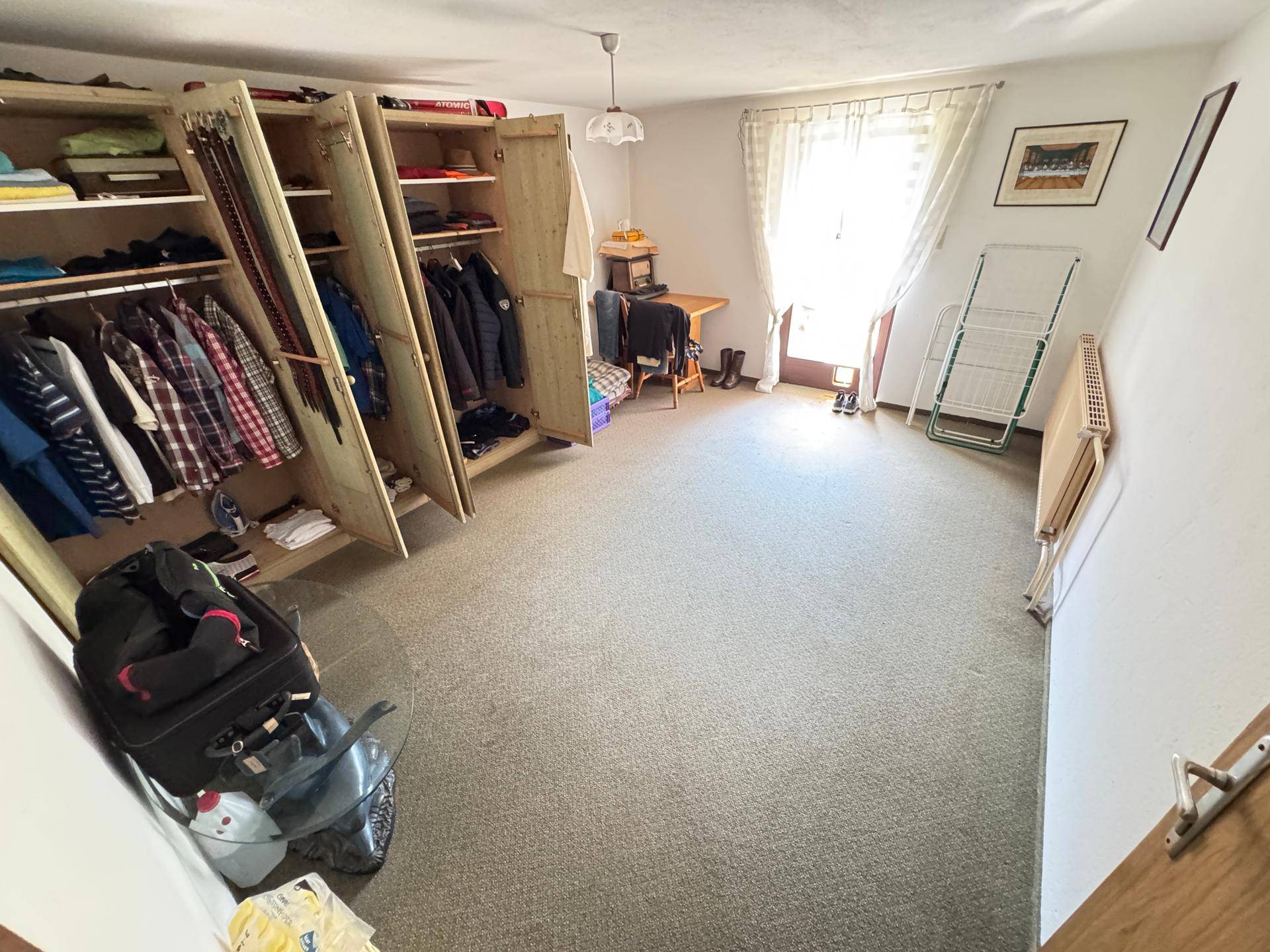 Schlafzimmer mit großen Holzschränken, Teppichboden und direktem Zugang zum Außenbereich.