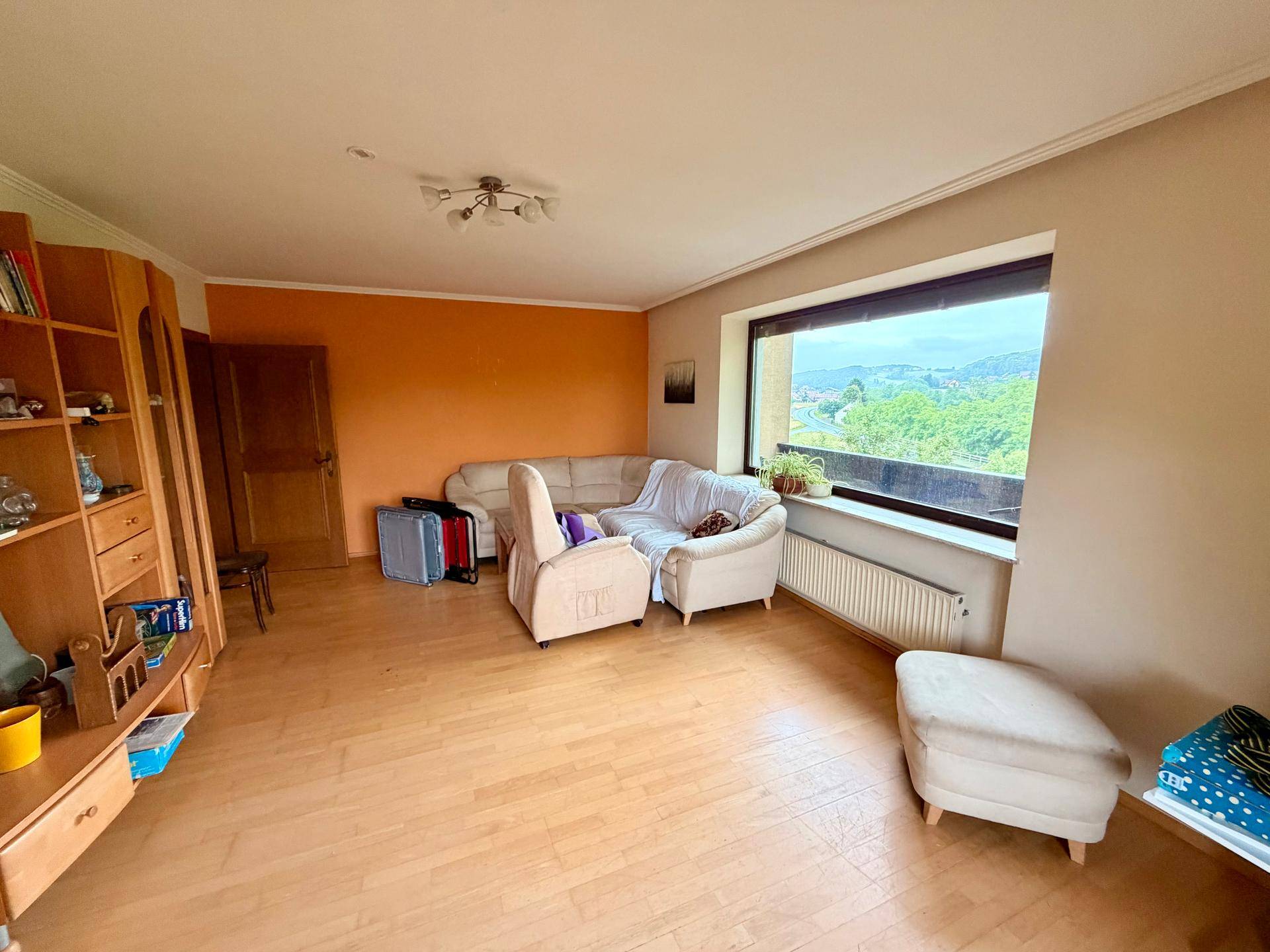 Helles Wohnzimmer mit Laminatboden, Holzmöbeln und weitem Ausblick.