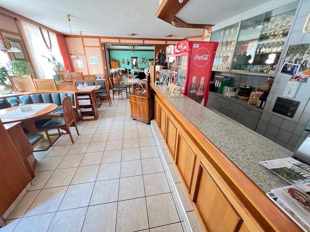 Thekenbereich mit Fliesenboden, Holzverkleidung und Getränkekühlschrank, ideal für Gastronomie.
