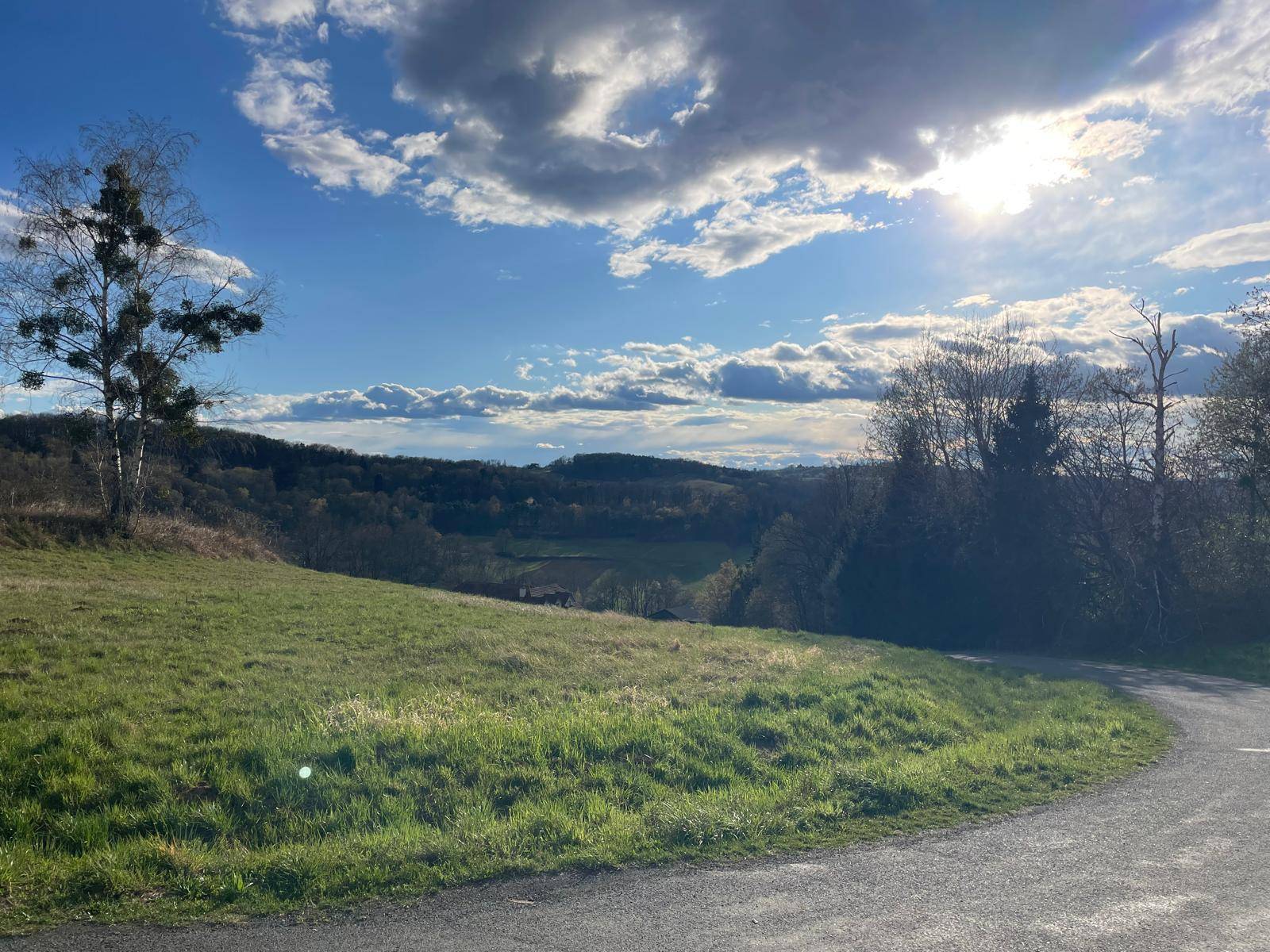 Grüne Hügellandschaft mit Panoramablick über Täler und Wälder unter einem sonnigen Himmel.