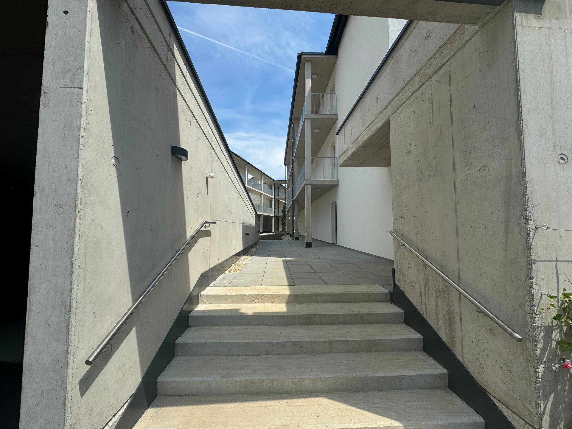 Einfahrt zur Tiefgarage mit Betonwänden und asphaltiertem Zugangsbereich.