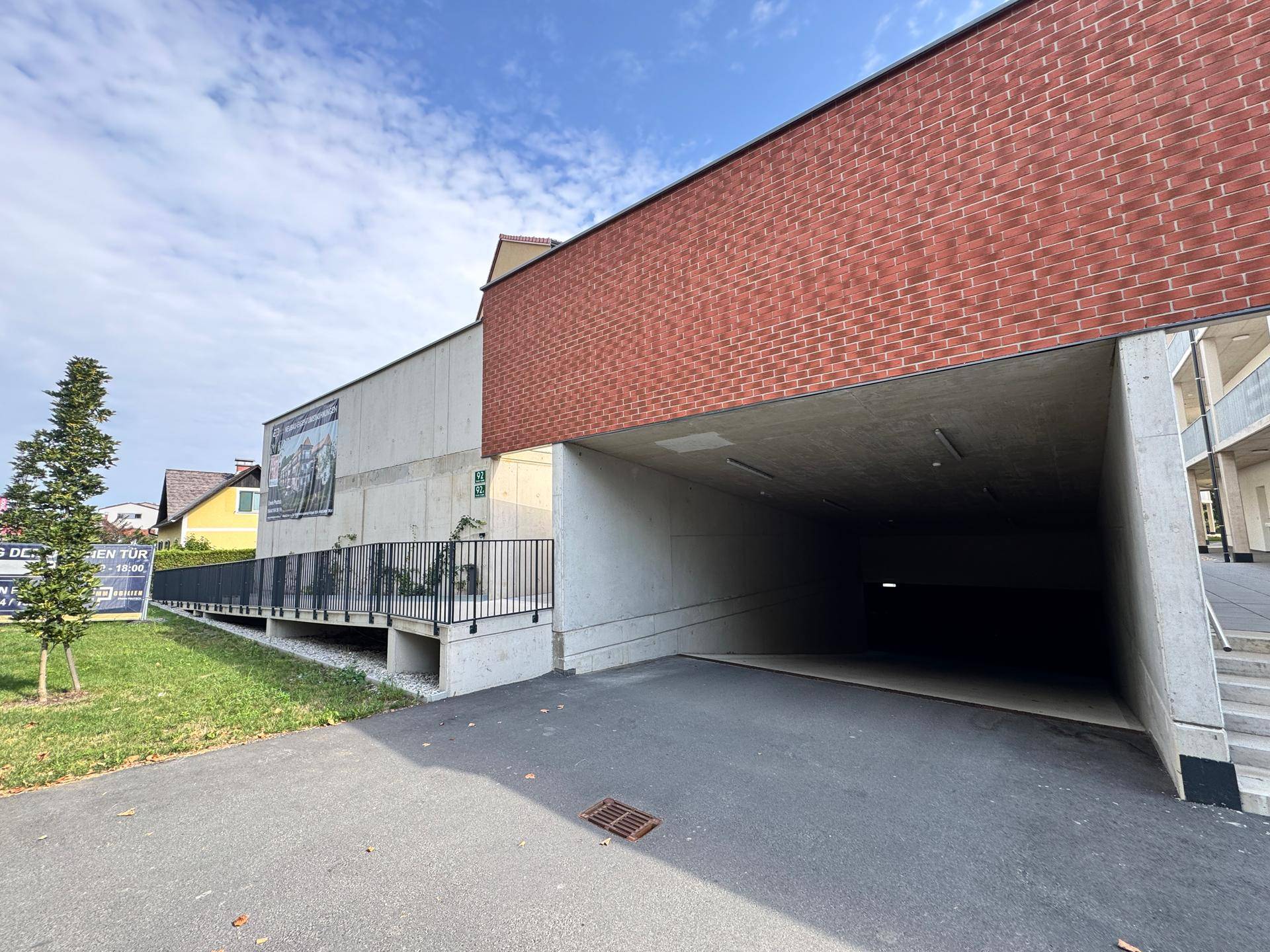 Eingang zur Tiefgarage eines modernen Wohnkomplexes mit Ziegel- und Betonfassade.
