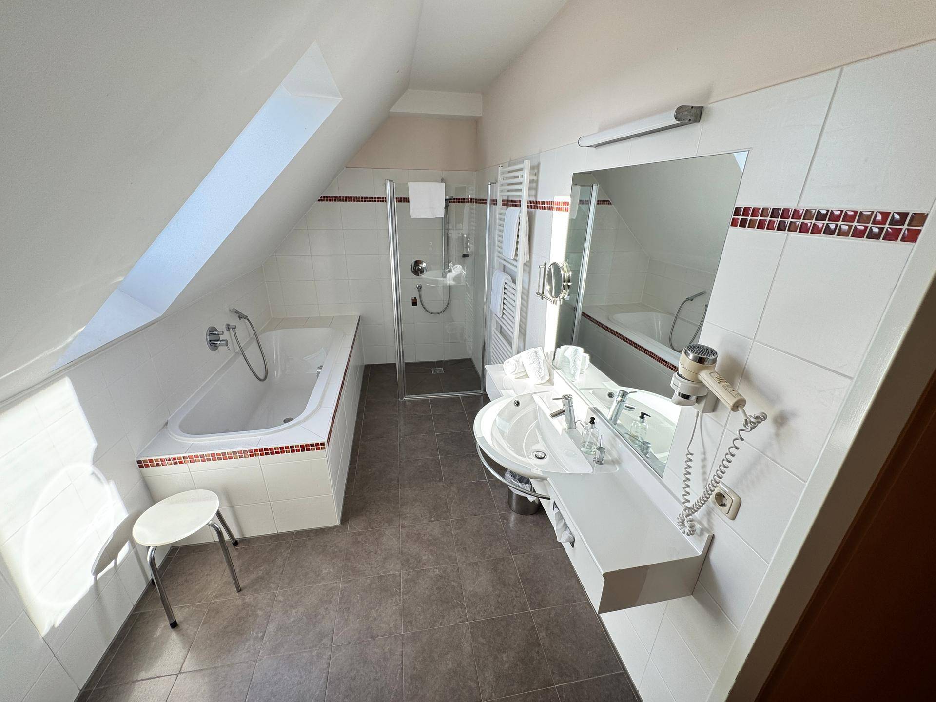 Badezimmer mit Badewanne, Duschkabine und Dachschräge.