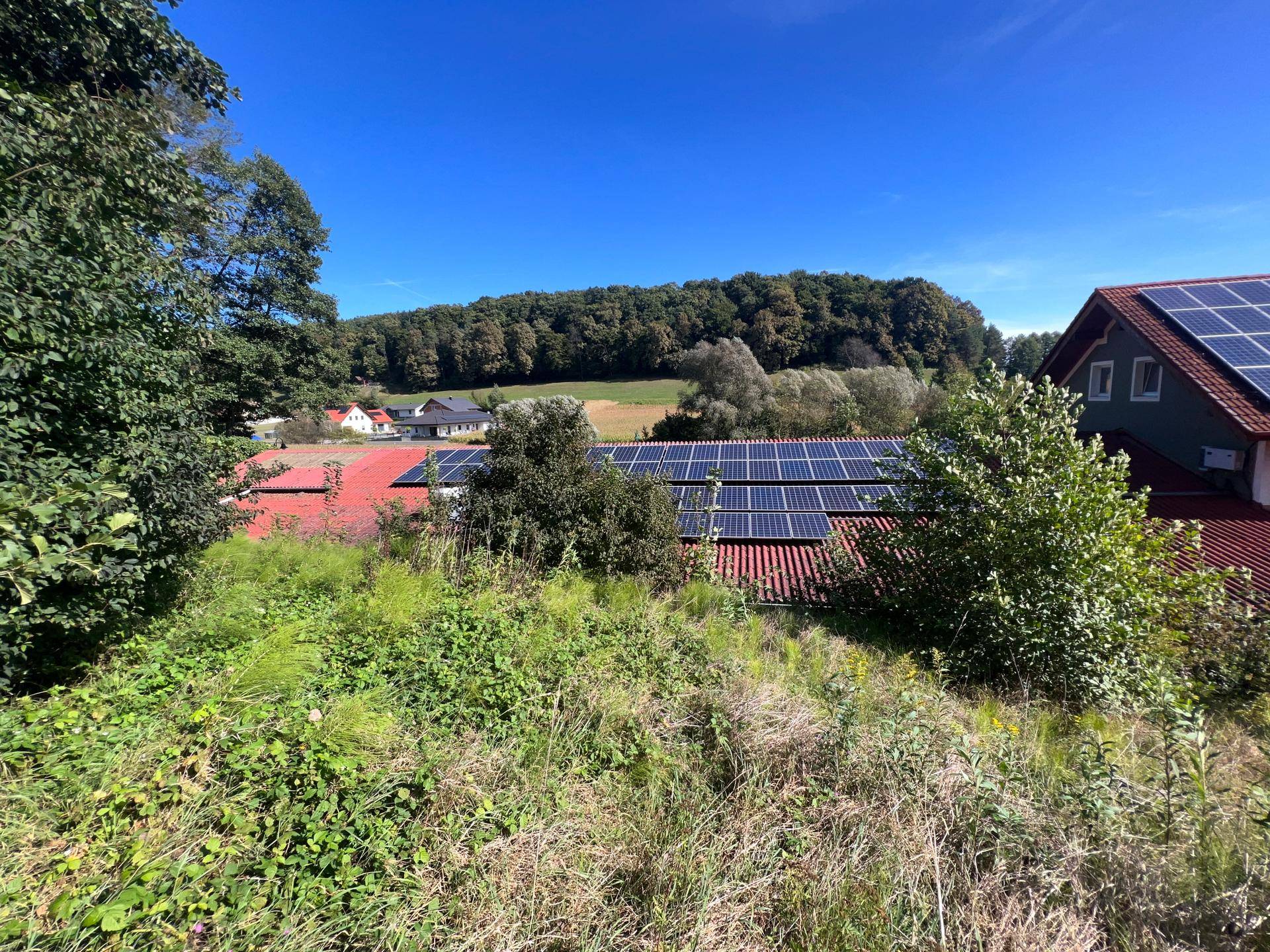 Weitläufige Ansicht des Daches mit Solaranlagen und der umliegenden grünen Landschaft und Feldern.