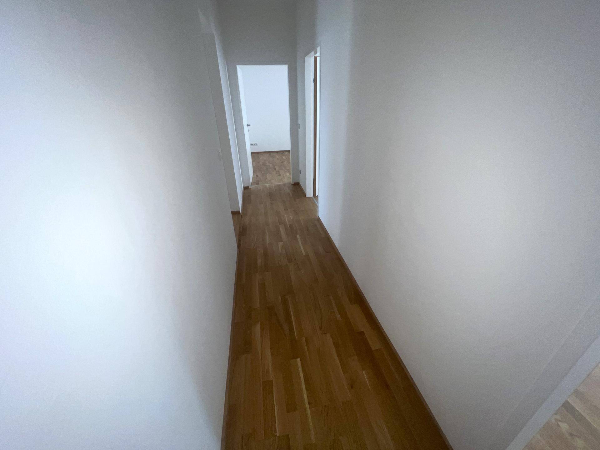 Heller Flur mit Parkettboden, der zu weiteren Räumen der Wohnung führt.