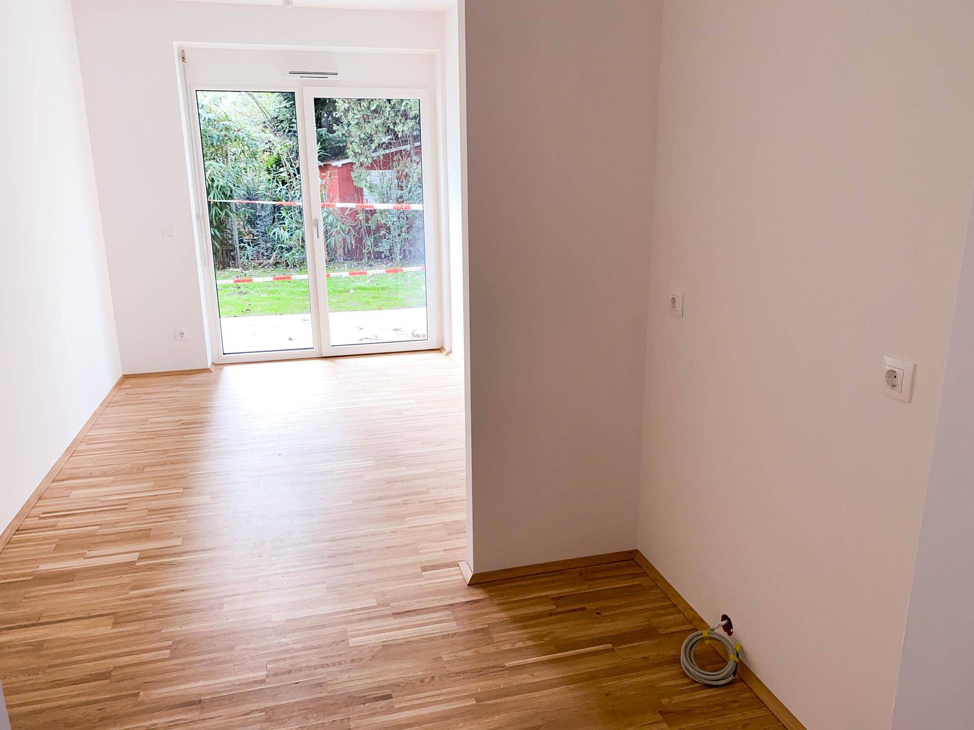 Heller Wohnraum mit Parkettboden und Zugang zum Garten, ideal für entspannte Stunden.