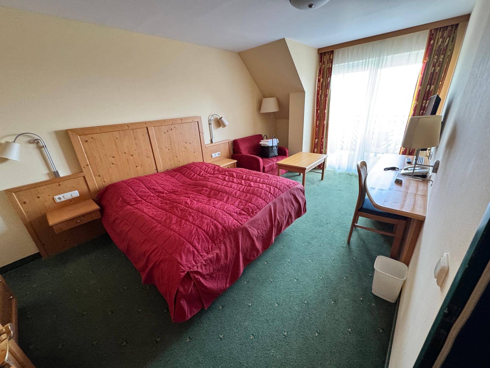 Schlafzimmer mit Doppelbett, Schreibtisch und Teppichboden.
