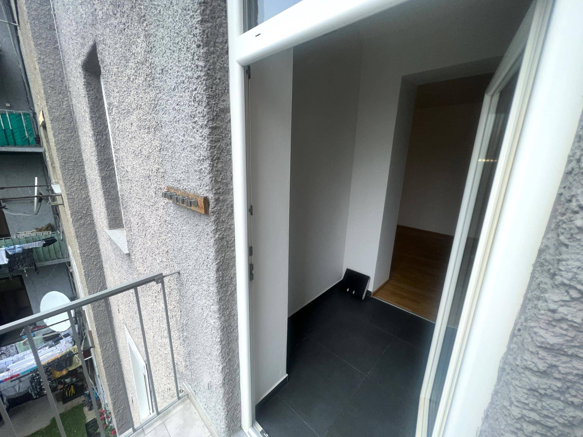 Zugang zu einem kleinen Balkon mit Fliesenboden und Blick auf die Umgebung.
