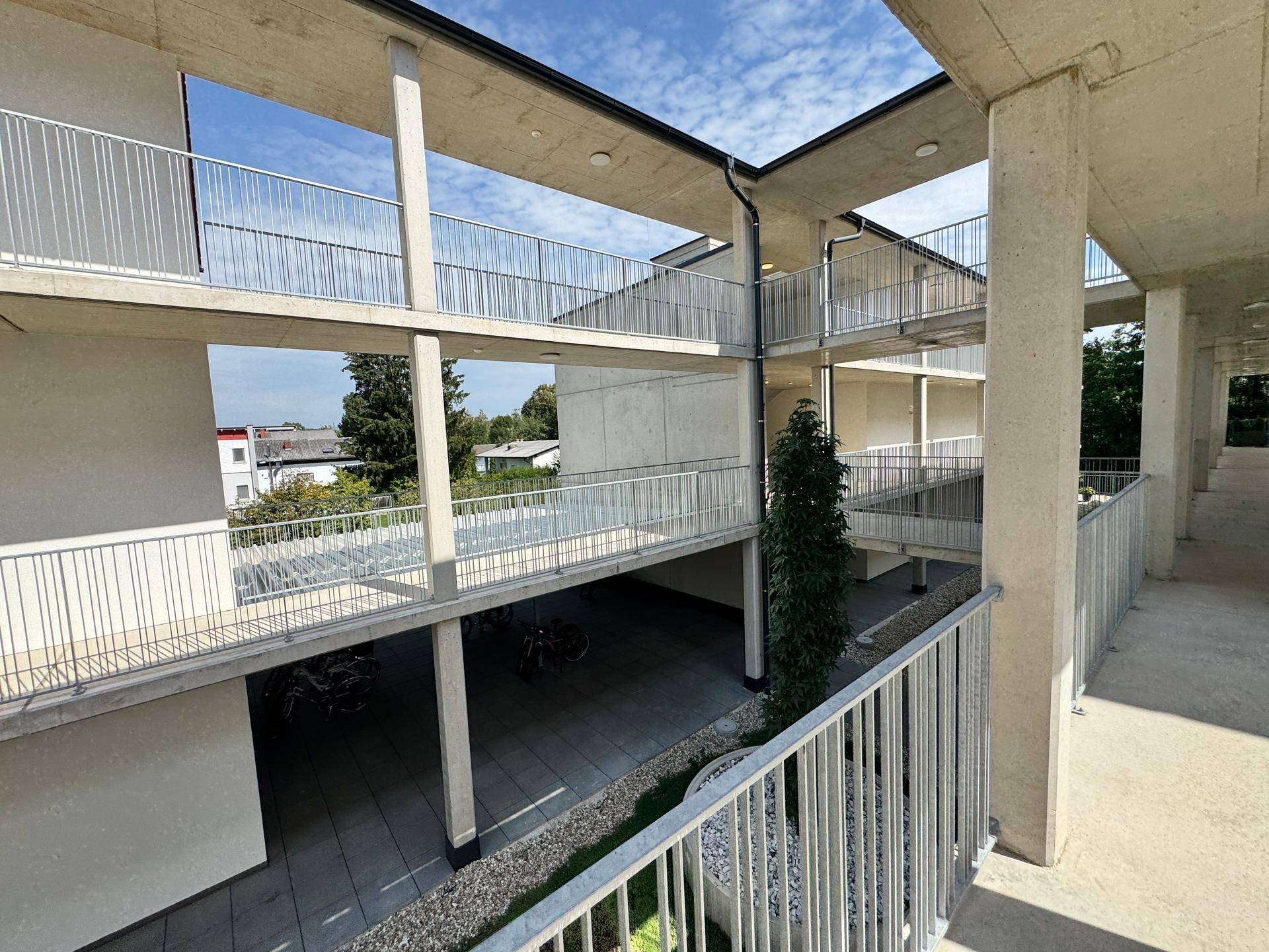 Offene Laubengänge und Balkone in einem modernen Wohnkomplex mit Blick auf den Innenhof.