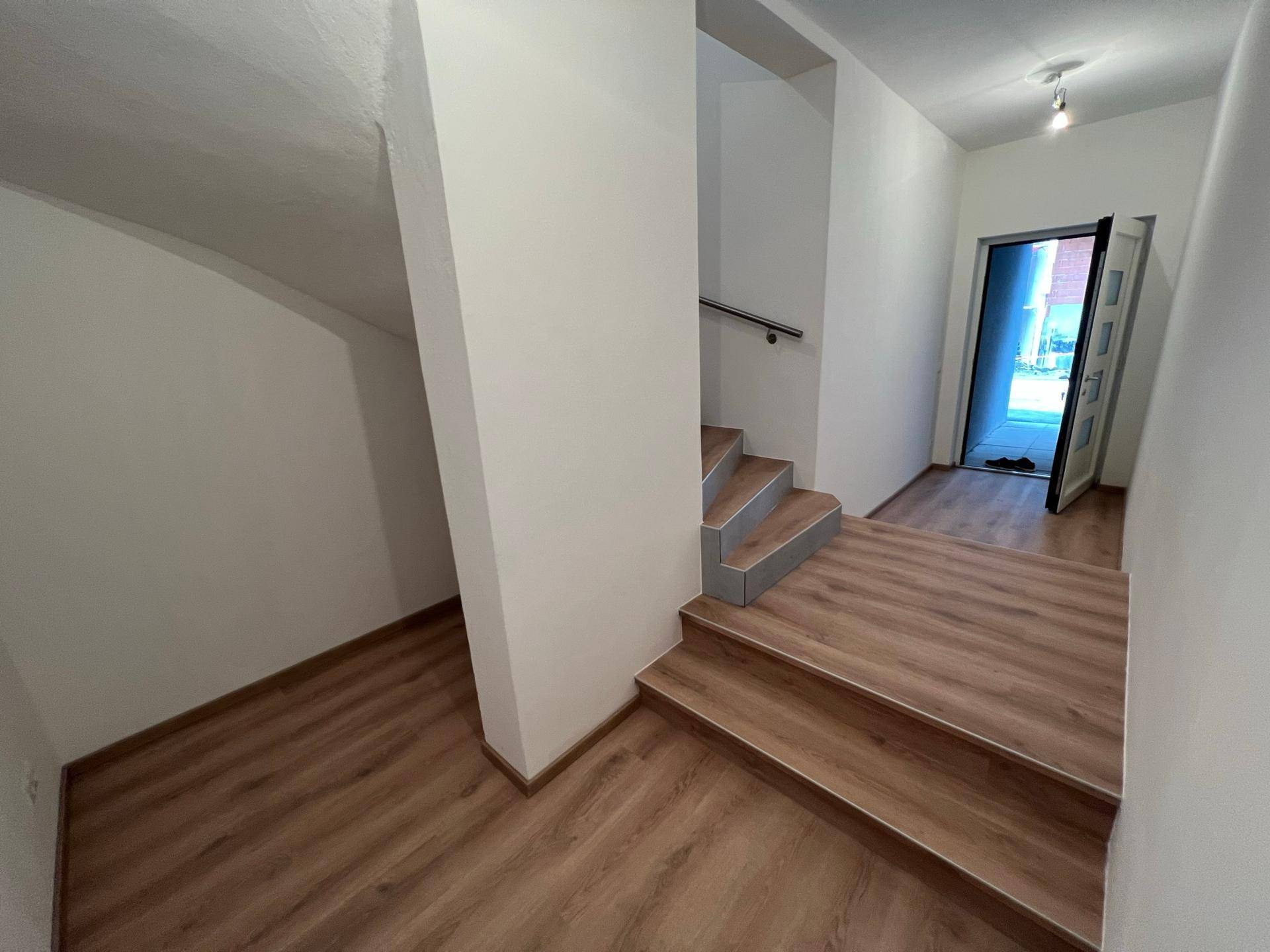 Treppenhaus mit Laminatstufen und weiß gestrichenen Wänden, führt in die obere Etage.