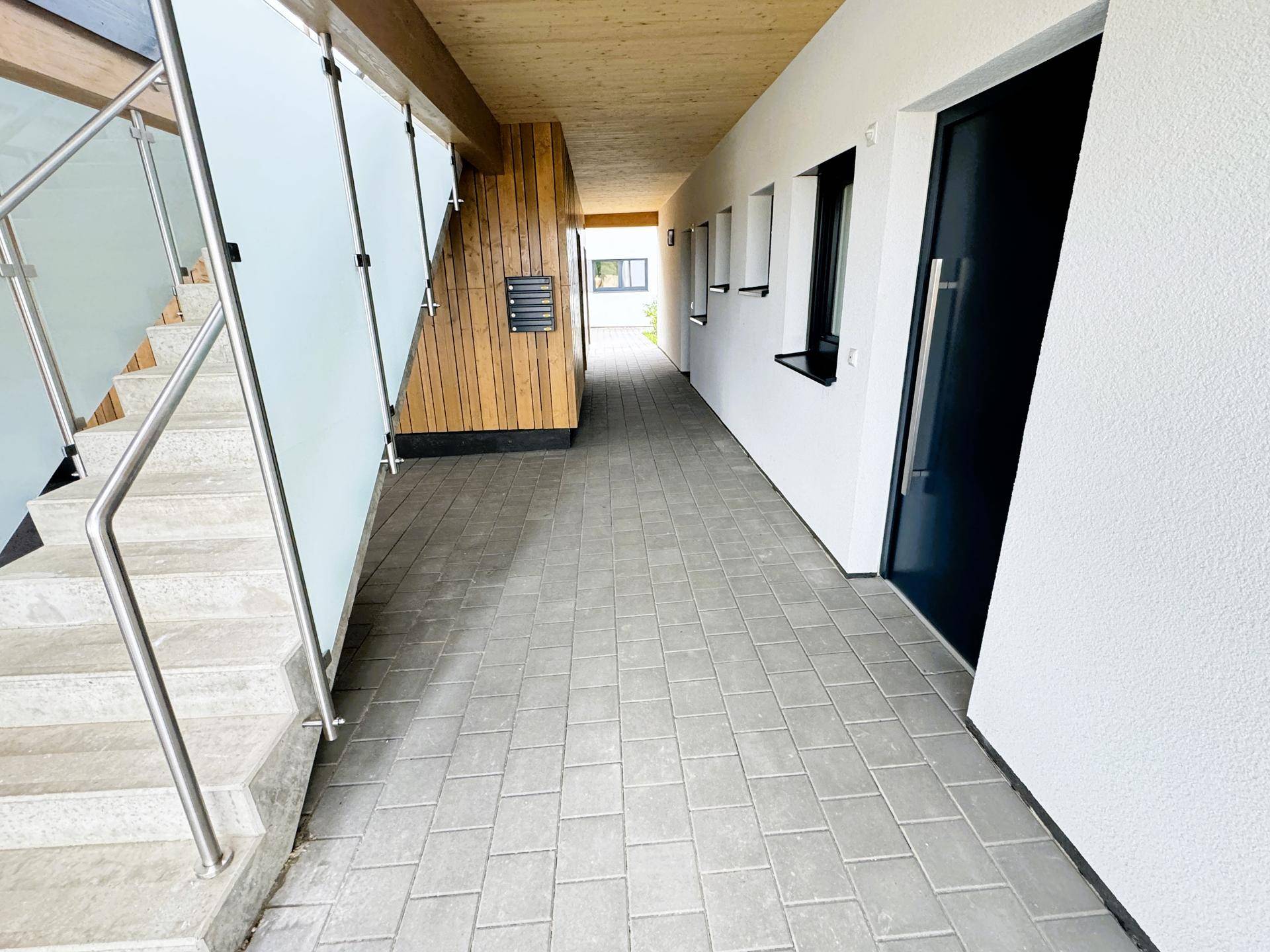 Überdachter Eingangsbereich mit Treppe, Fliesenboden und Briefkästen für mehrere Wohneinheiten.