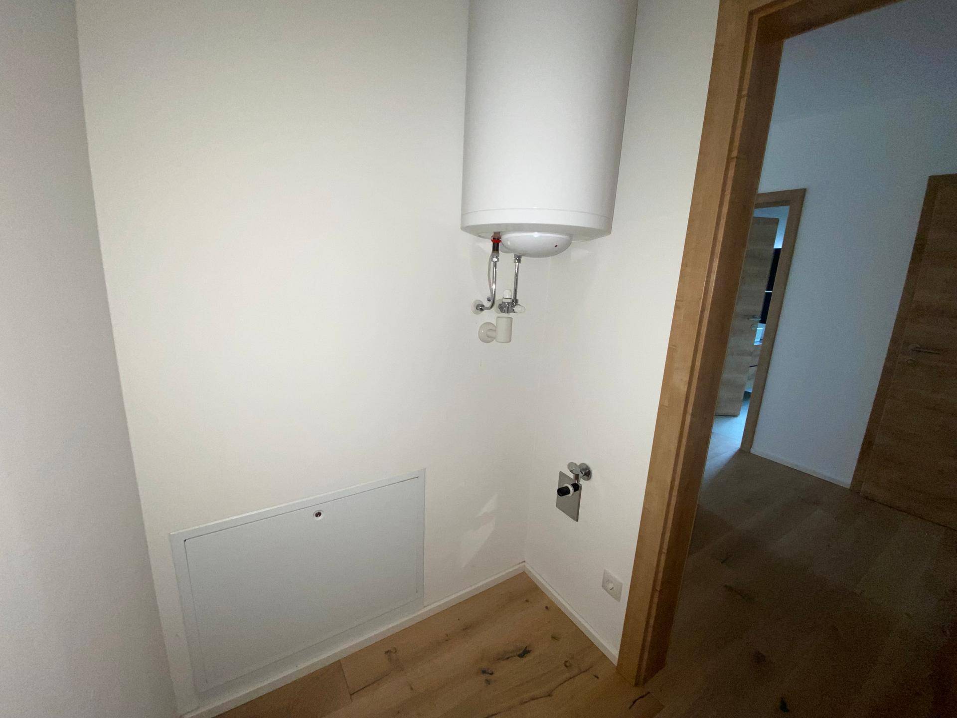 Kleiner Hauswirtschaftsraum mit Warmwasserboiler und Anschlussmöglichkeiten.