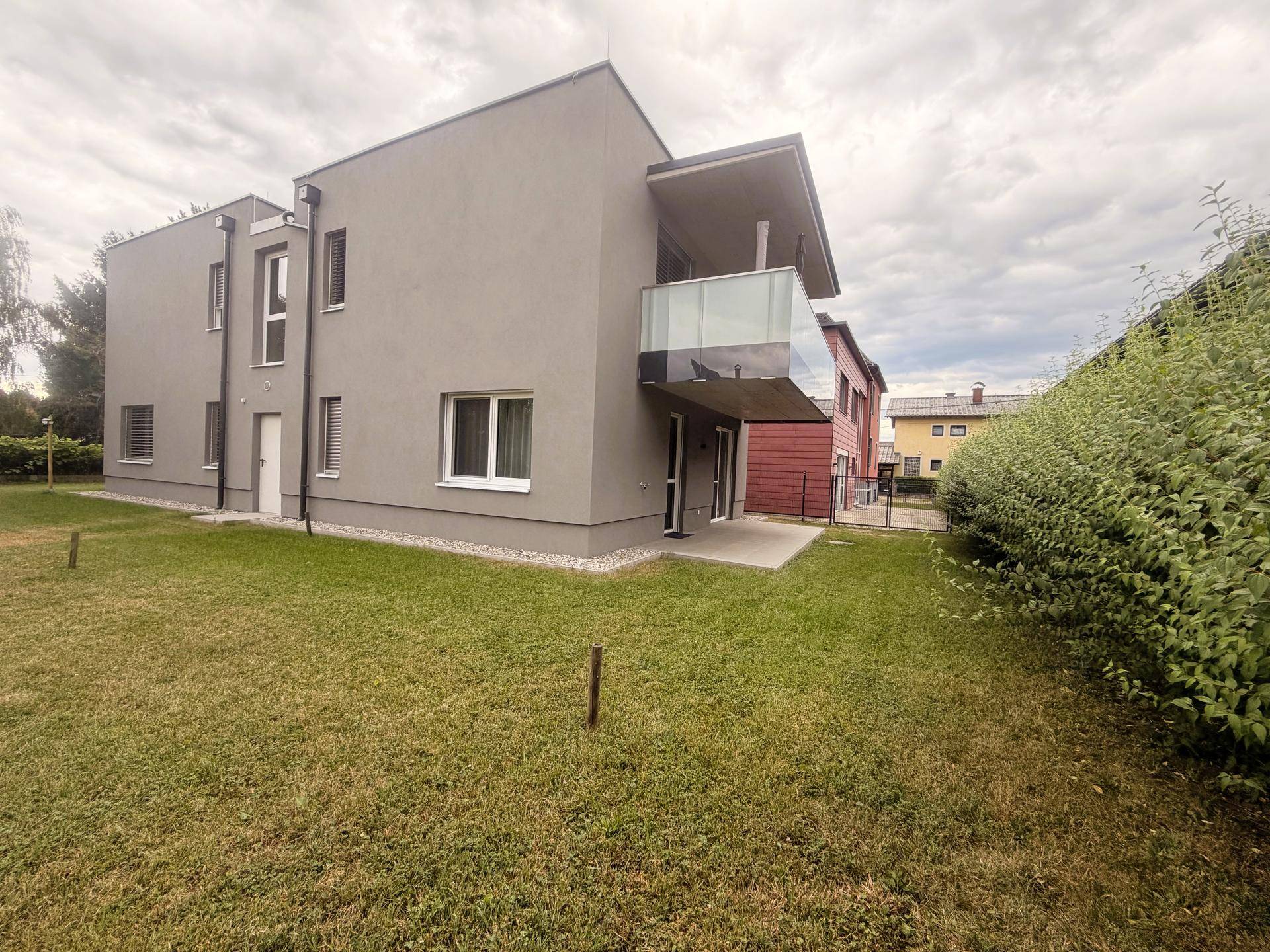 Modernes Mehrfamilienhaus mit Balkon und Gartenanlage.