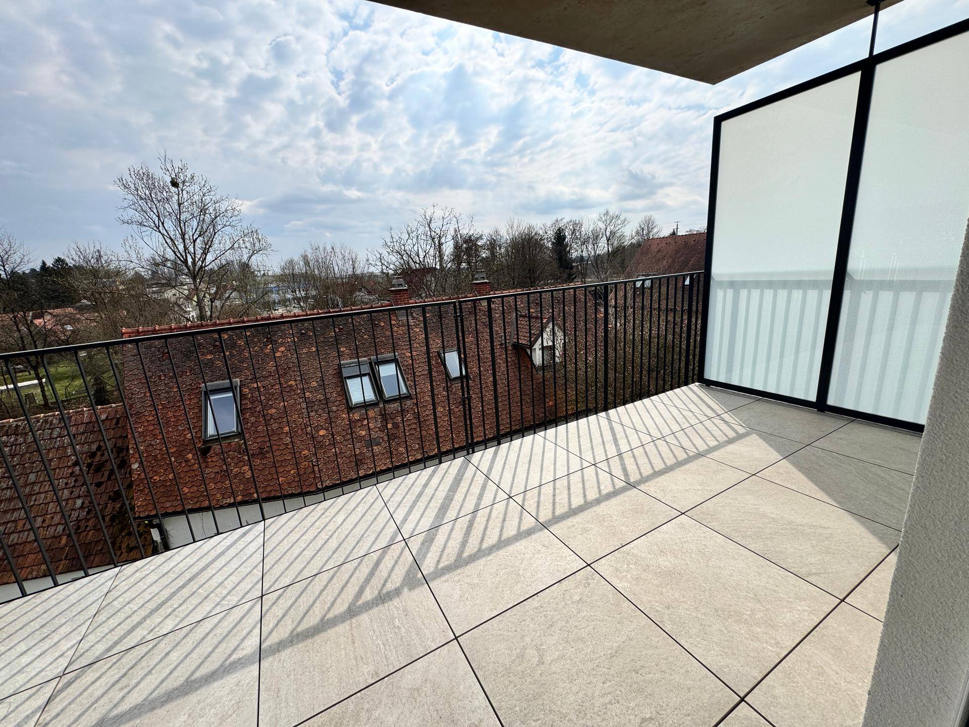 Geräumiger Balkon mit Fliesenboden und Blick über die Dächer der Stadt.