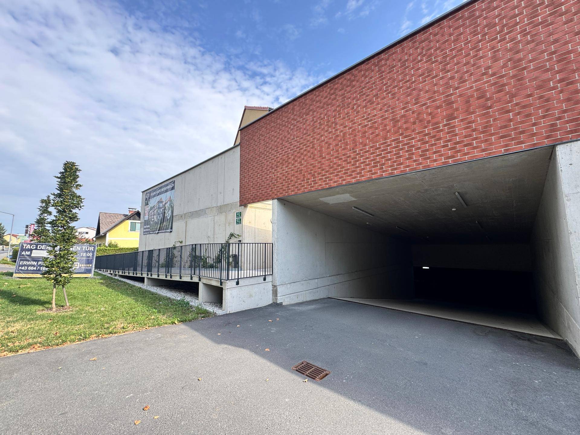 Einfahrt zu einer Tiefgarage mit Ziegelmauerwerk und Betonwänden.