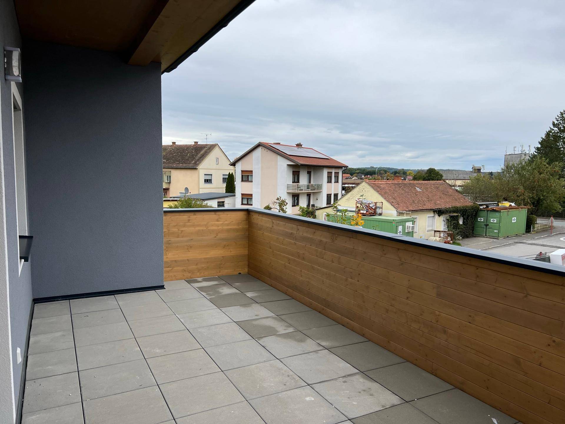 Geräumiger Balkon mit Holzwänden und Fliesenboden, bietet Platz für Entspannung im Freien.