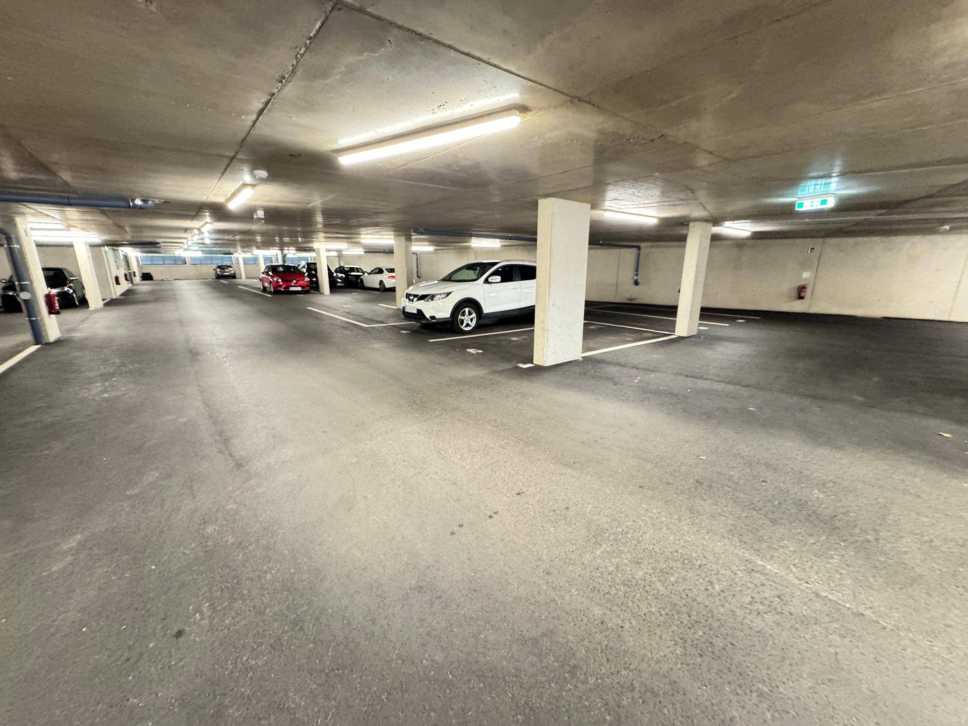Tiefgarage mit geparkten Autos und ausreichend Platz für weitere Fahrzeuge, sauber und organisiert.