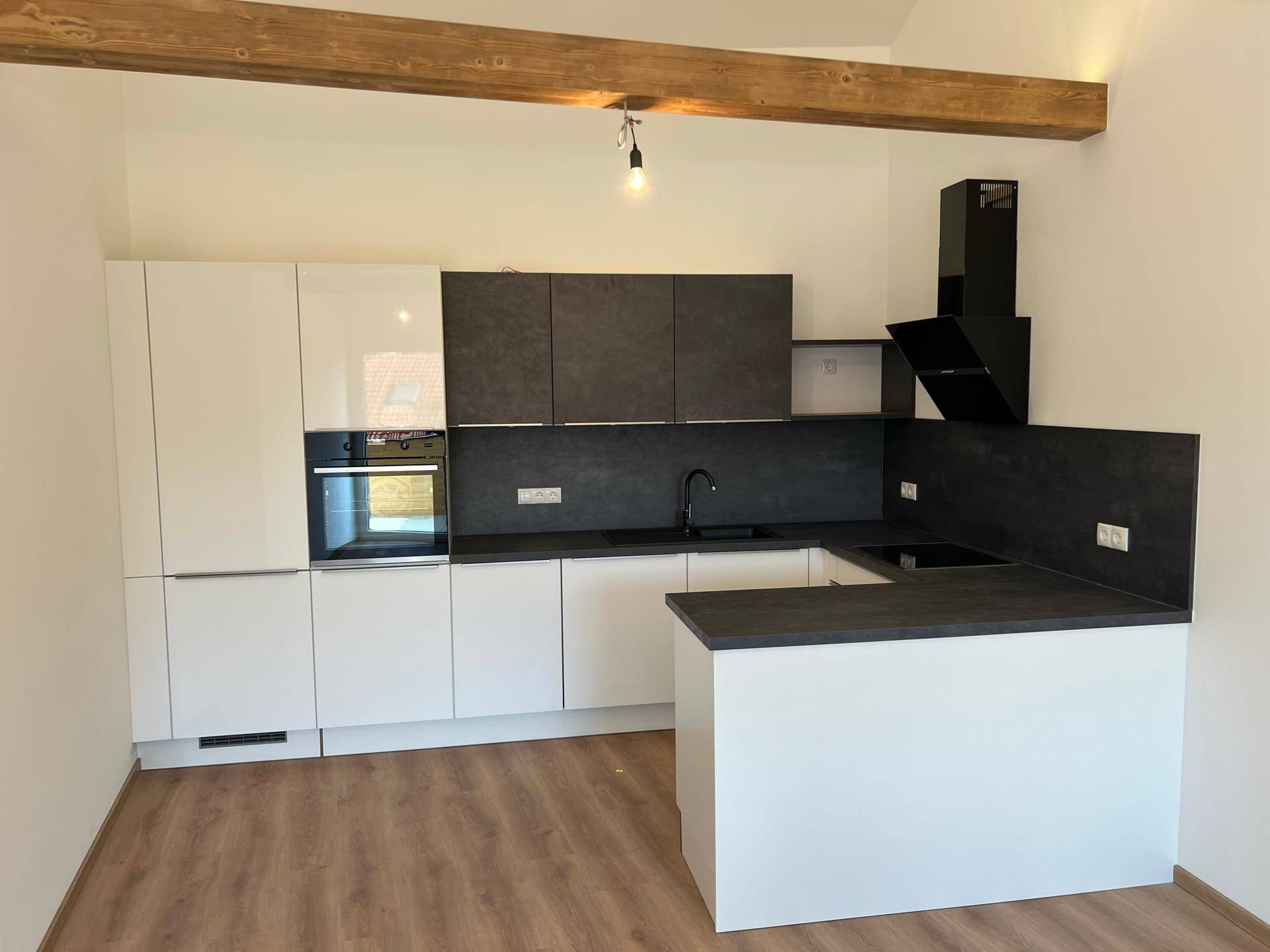 Moderne Einbauküche mit weißen und anthrazitfarbenen Schränken, Holzbalken und neuen Geräten.