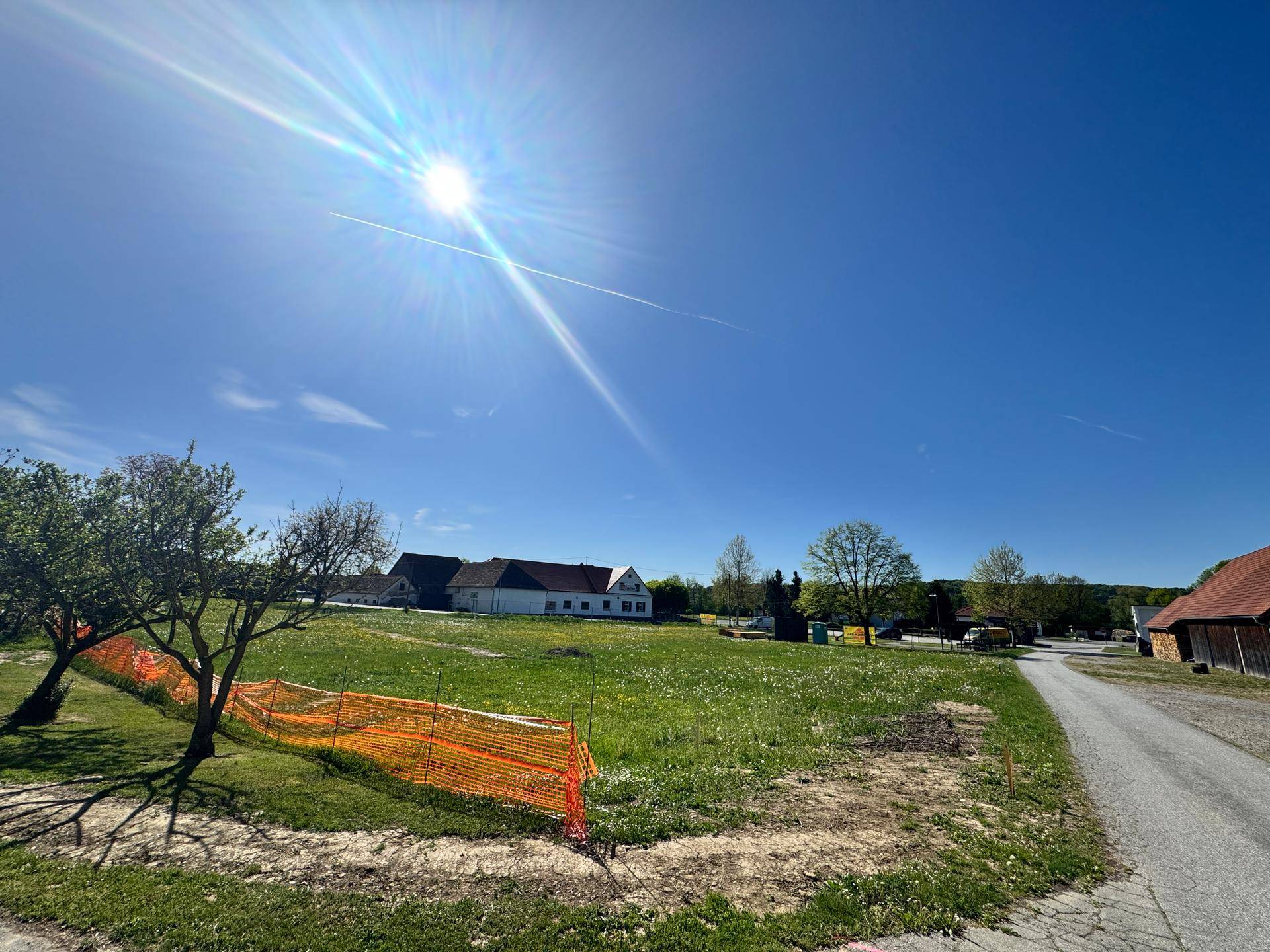Sonniges, offenes Grundstück mit grüner Wiese und Blick auf die ländliche Umgebung und Häuser.