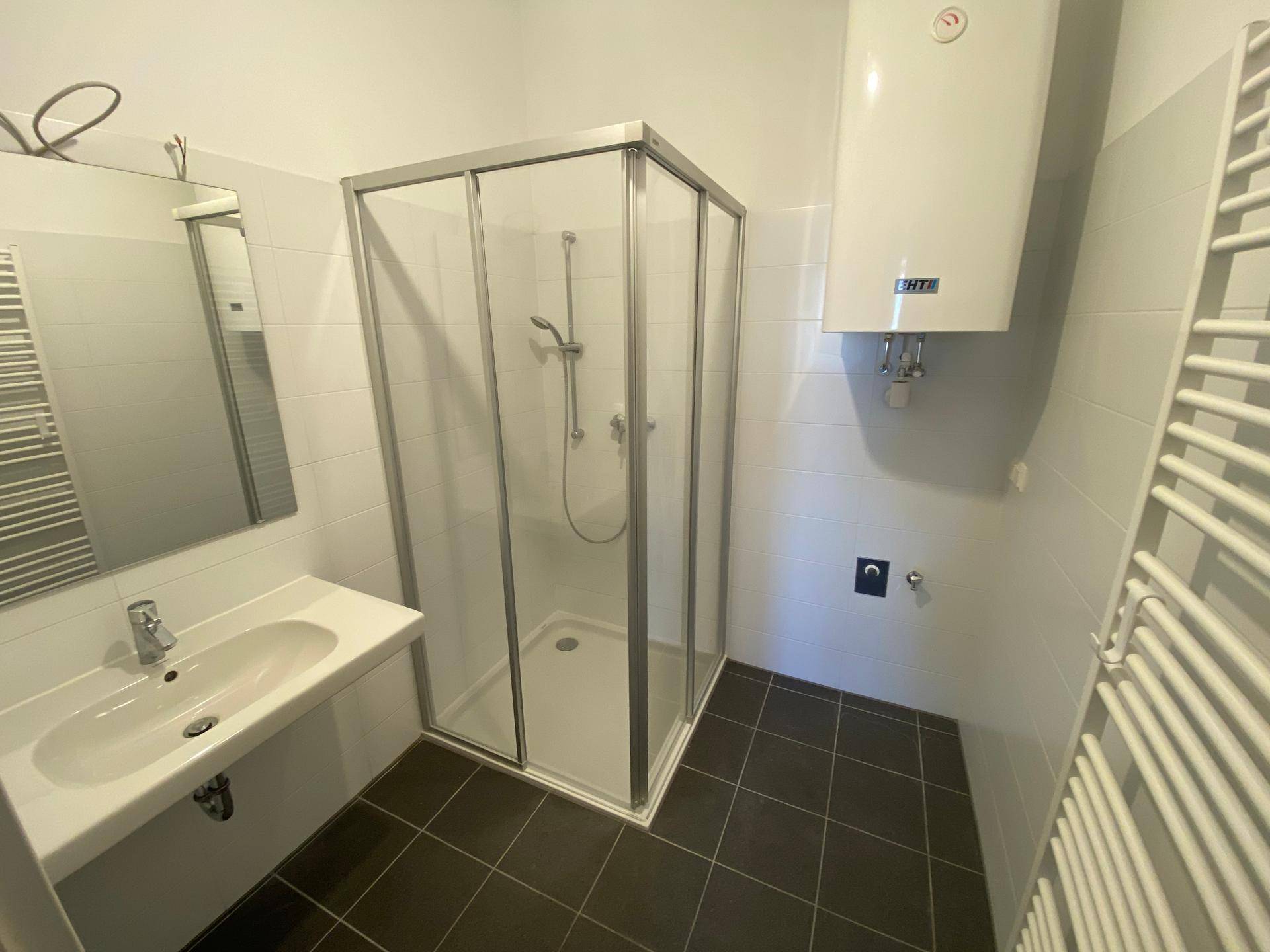 Modernes Badezimmer mit Duschkabine, Waschbecken, Spiegel und beheiztem Handtuchhalter.