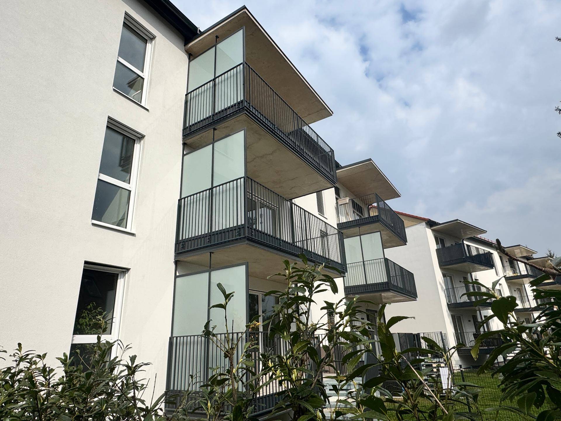 Fassade eines modernen Wohngebäudes mit gestaffelten Balkonen und großen Fenstern.