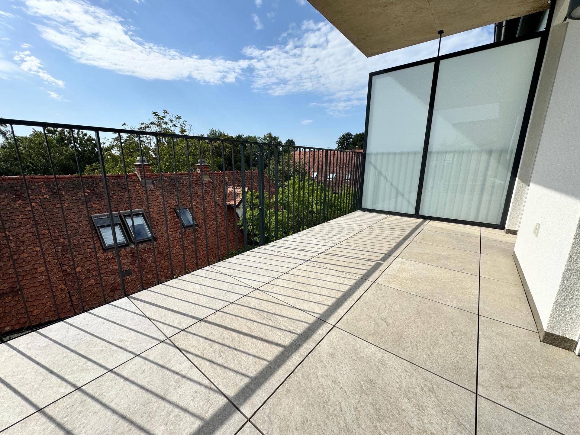 Großer Balkon mit Fliesenboden und modernem Geländer, ideal für entspannte Stunden im Freien.