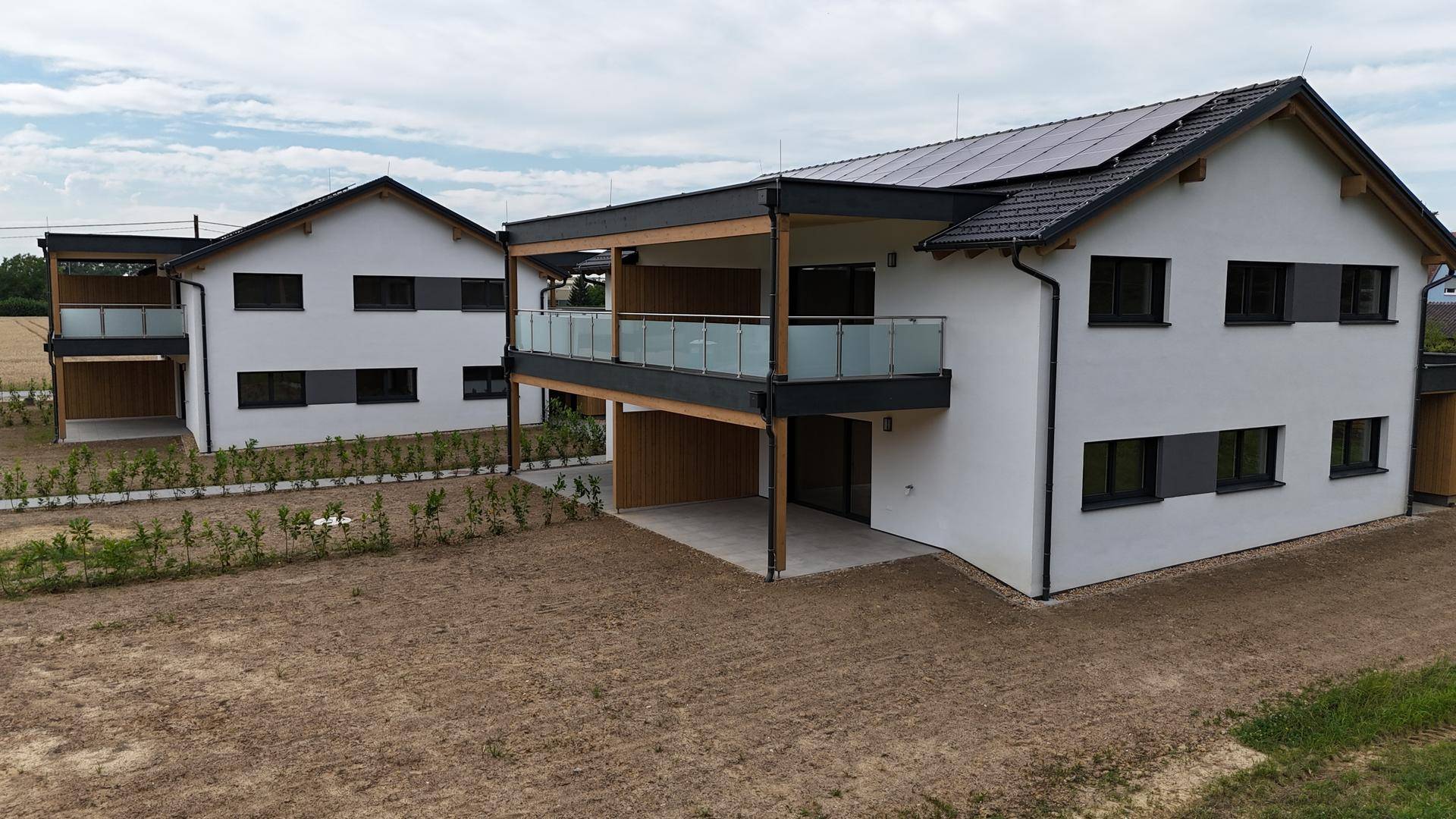 Luftaufnahme von zwei modernen Doppelhaushälften mit Solaranlagen und Balkonen.