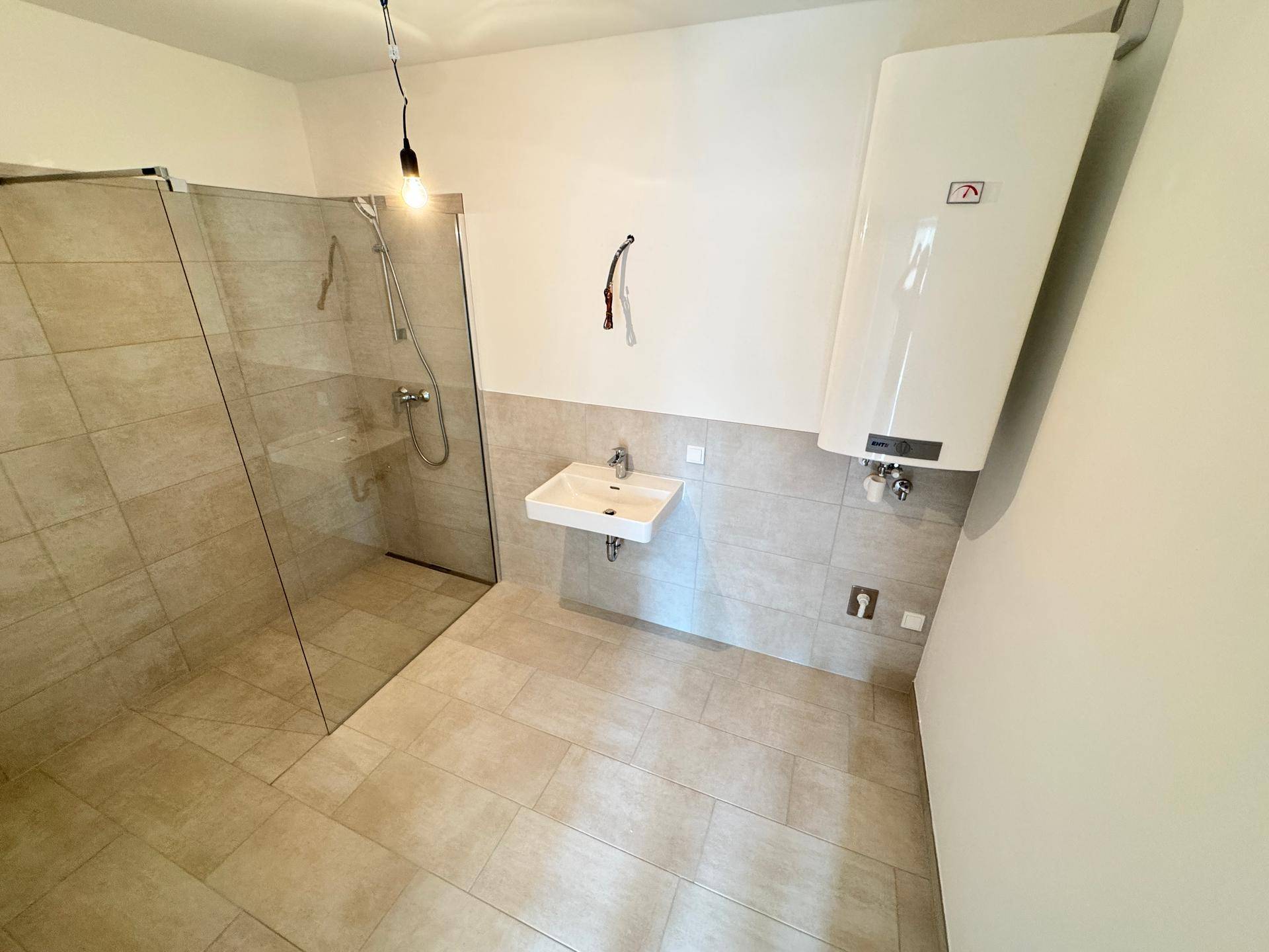Modernes Badezimmer mit begehbarer Dusche, Waschbecken und Boiler, hell gefliest.