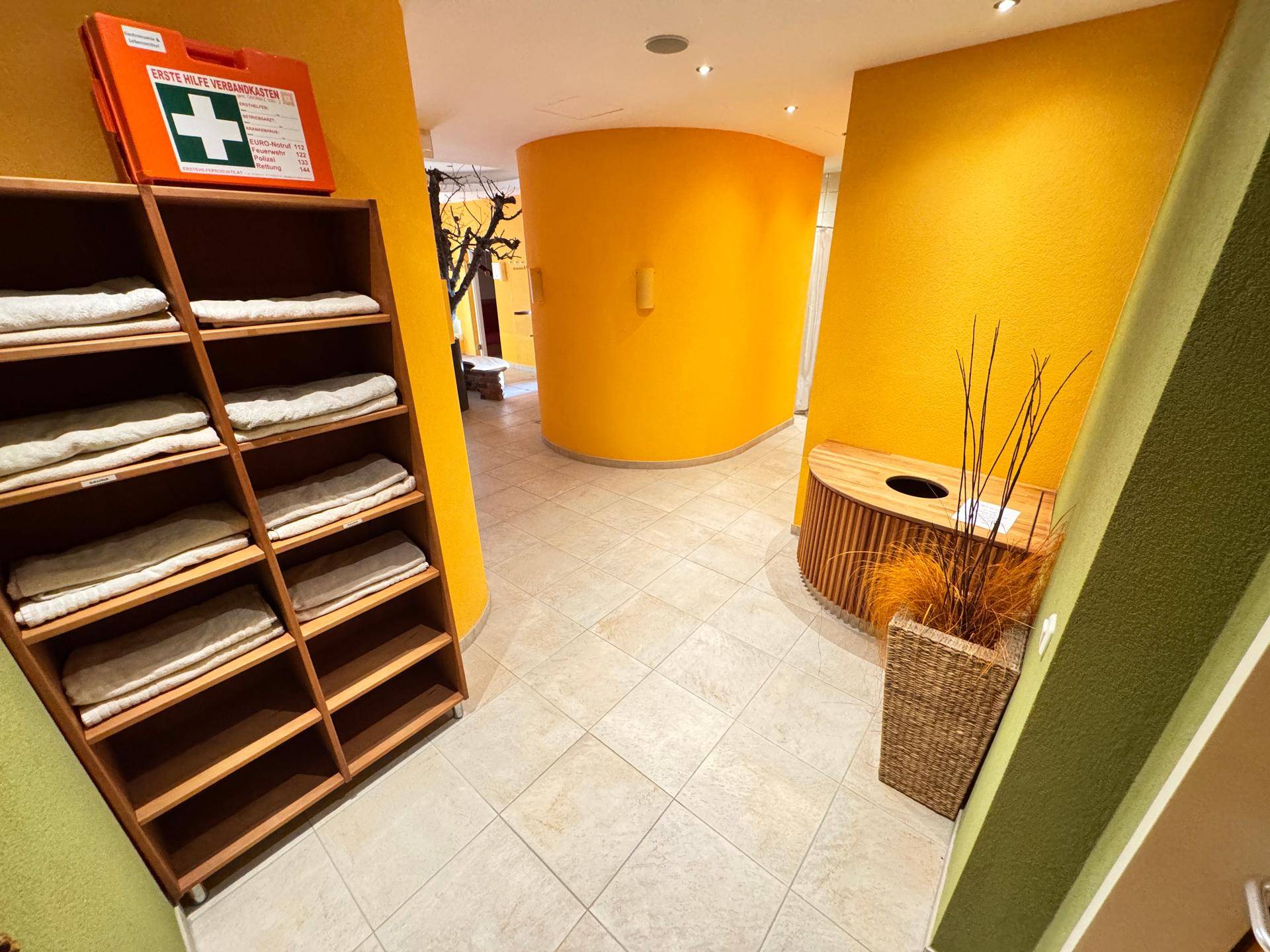 Wellnessbereich mit Handtuchregal und heller Fliesenboden.