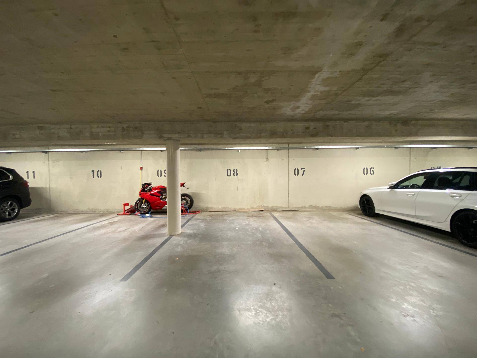 Tiefgarage mit nummerierten Stellplätzen und Betonwänden, bietet sichere Parkmöglichkeiten.